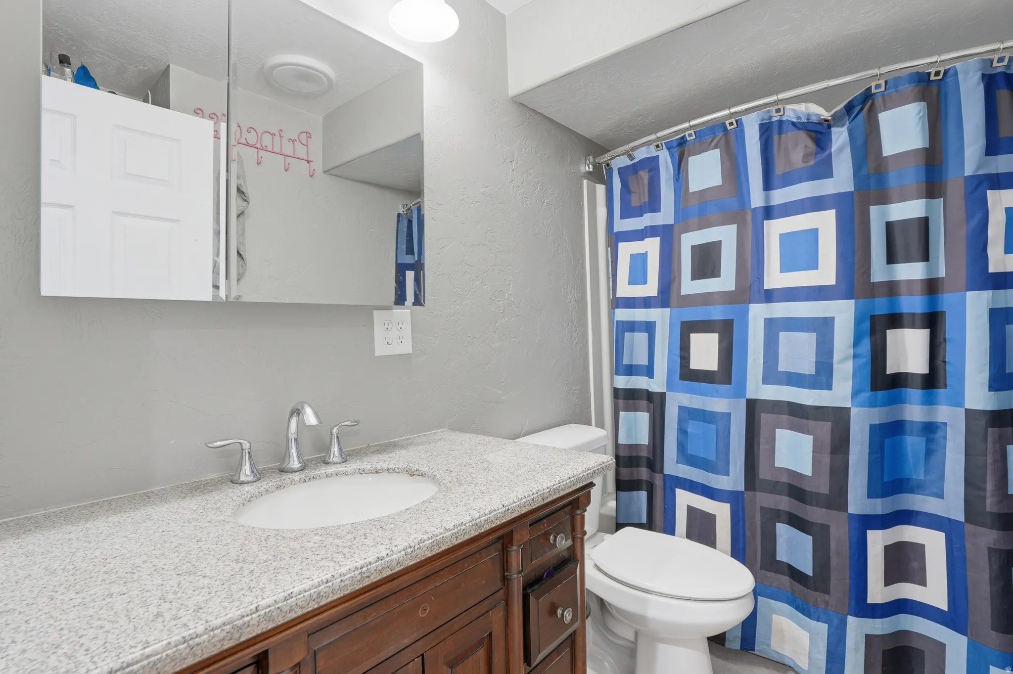 Bathroom with a textured wall, vanity, and a shower with curtain