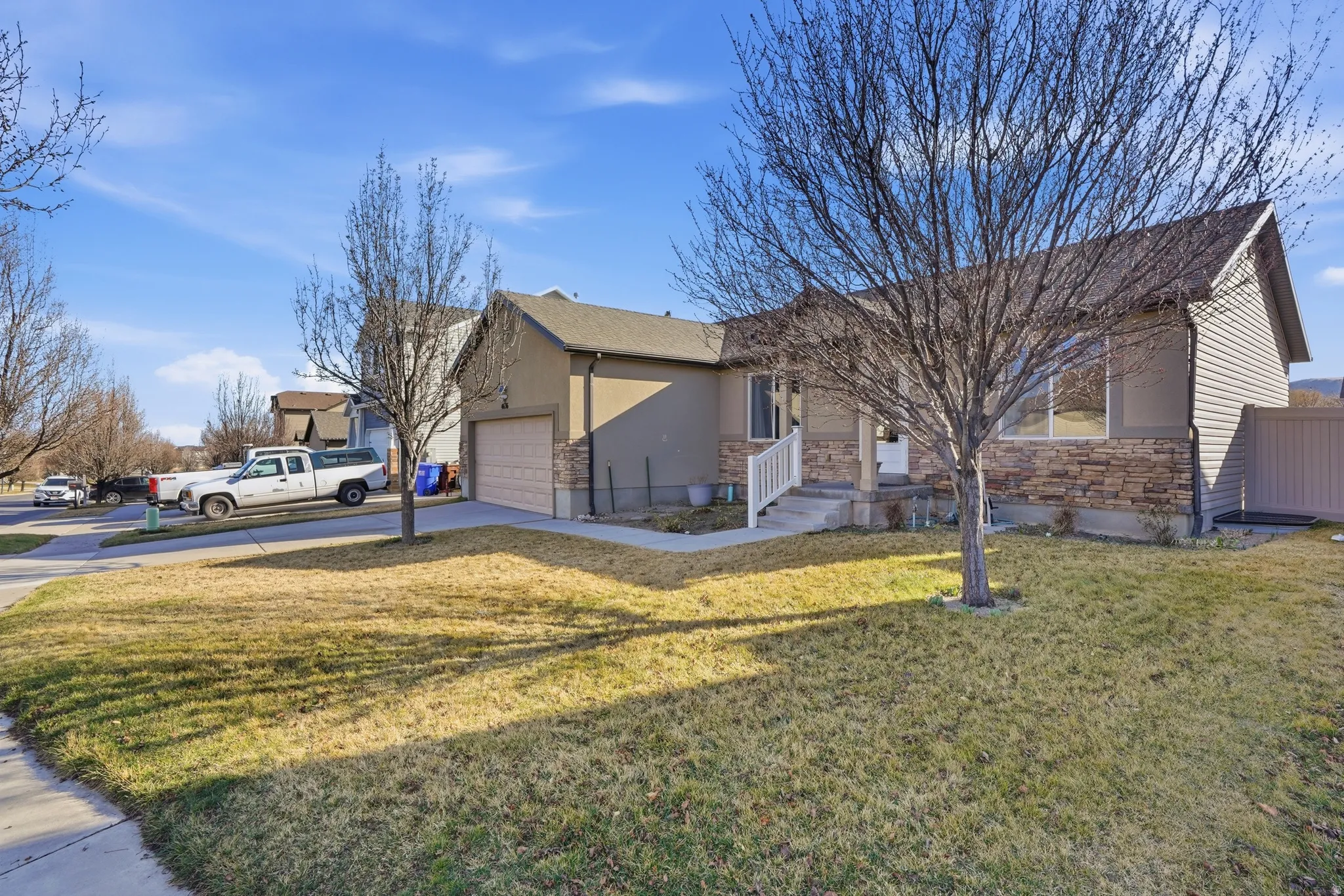 View of front facade featuring stone siding, a front yard, concrete driveway, and a garage
