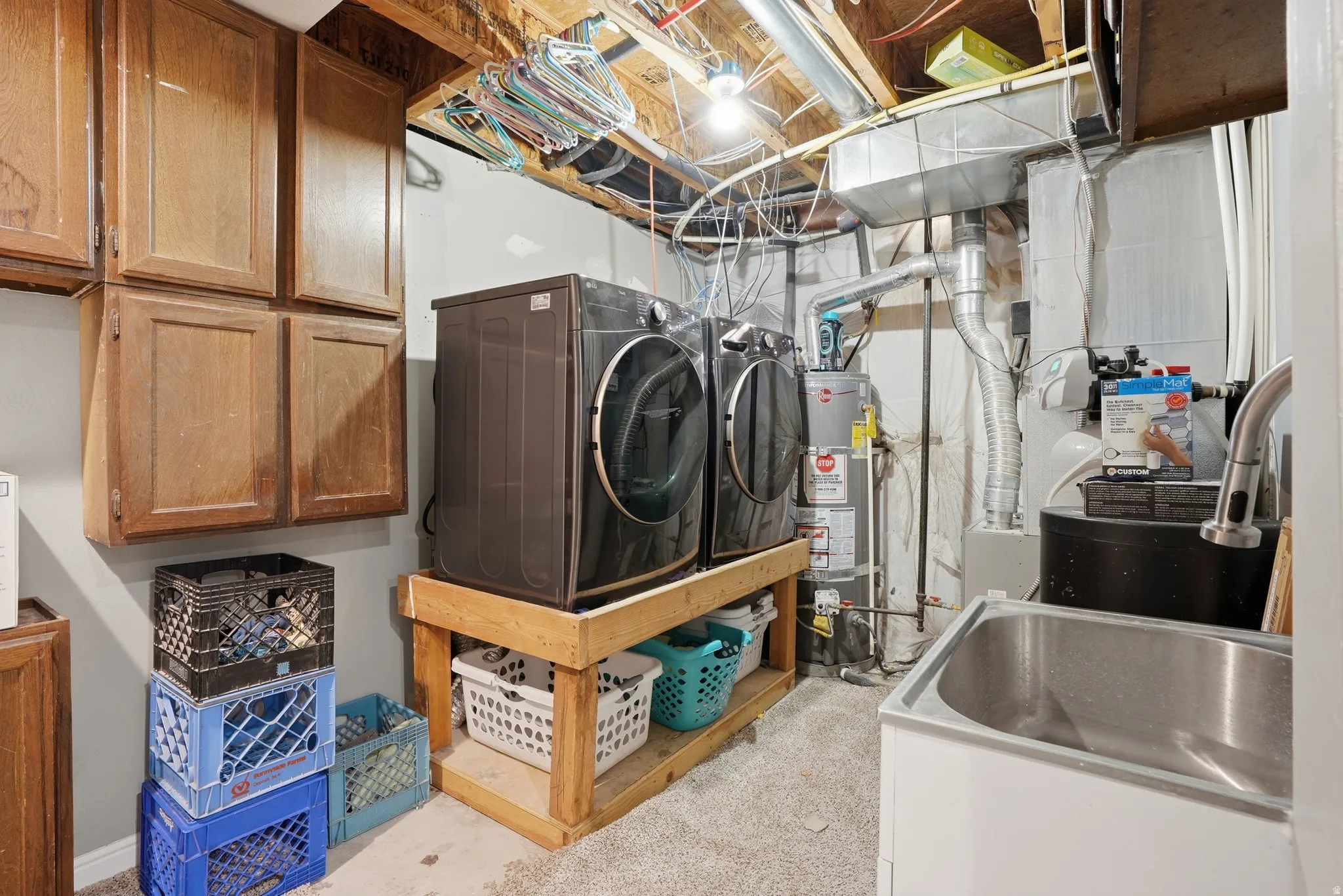 Laundry area with secured water heater, concrete floors, and independent washer and dryer