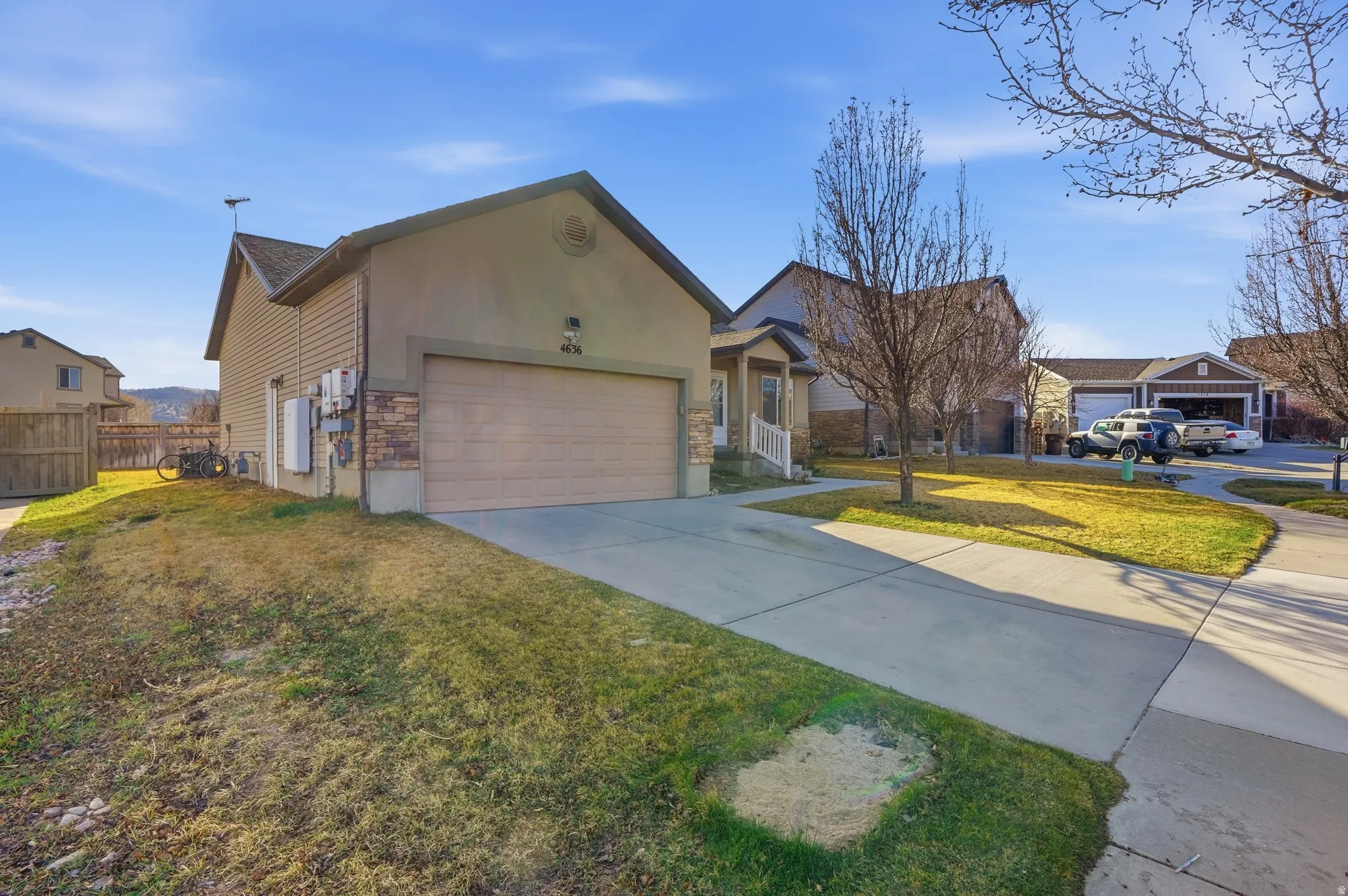 View of front of property with driveway, an attached garage, stucco siding, and stone siding