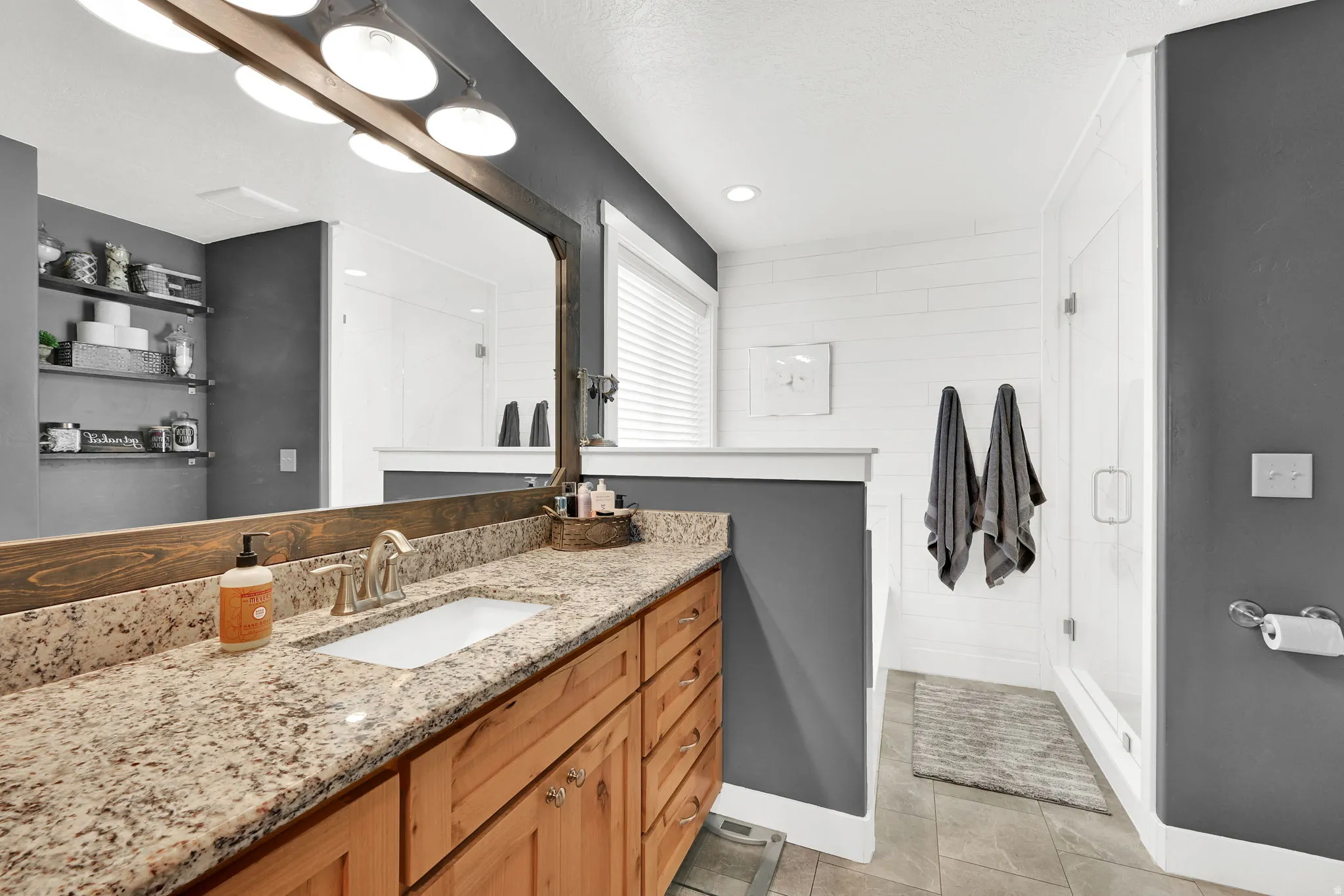 Full bathroom featuring a shower stall, vanity, and light tile patterned flooring