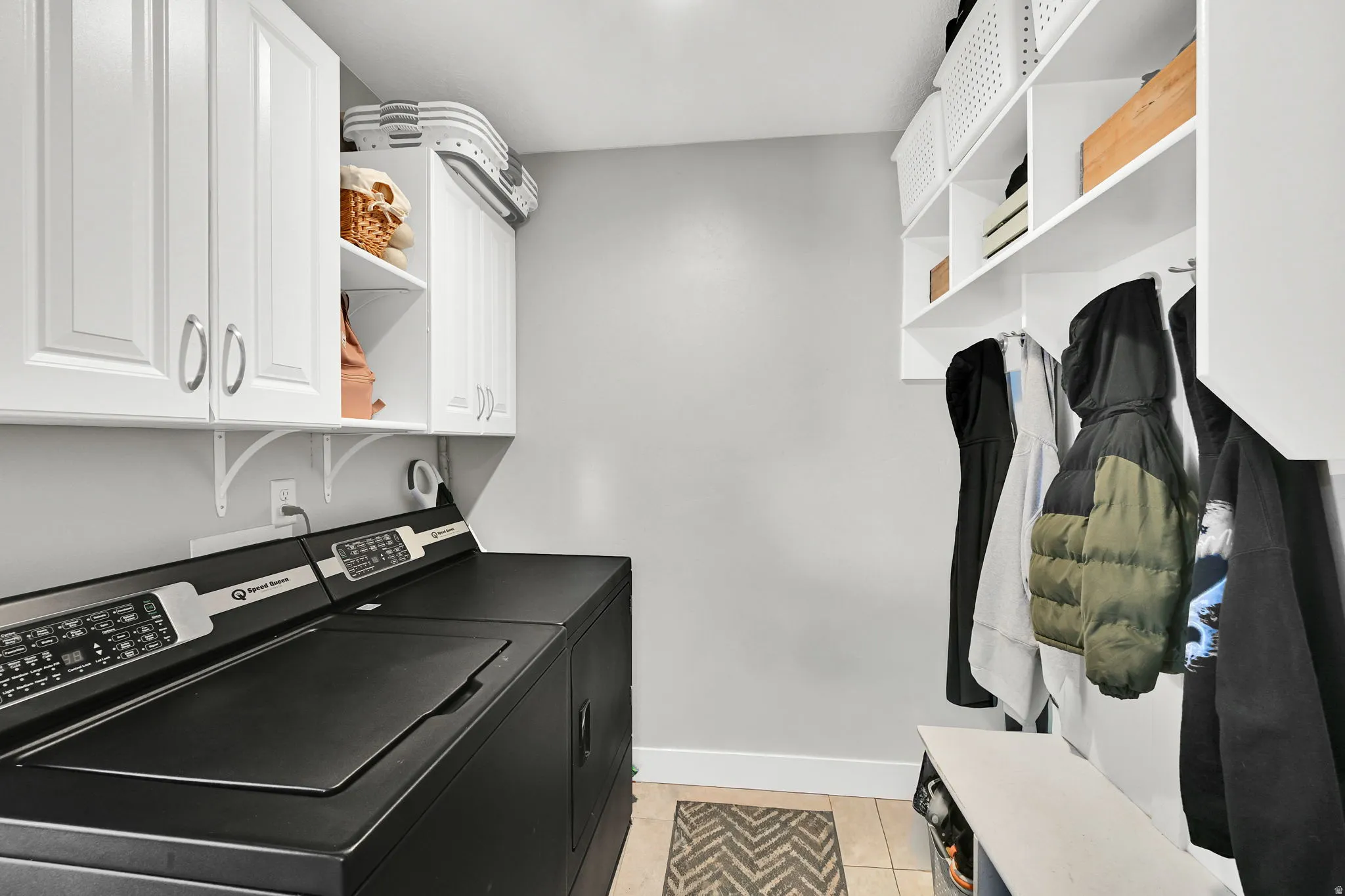 Laundry area with cabinet space, light tile patterned flooring, and washer and dryer