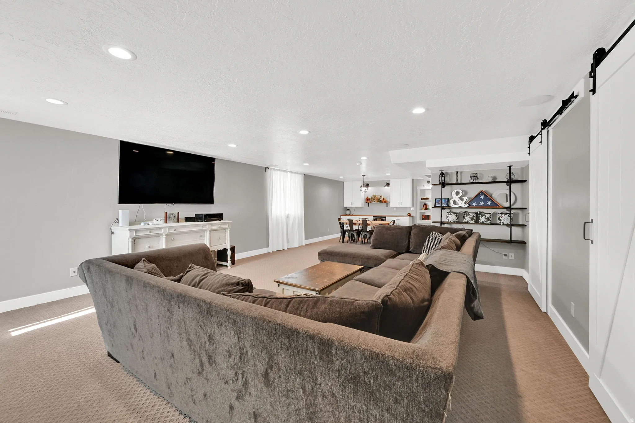 Living area with a barn door, recessed lighting, carpet floors, and a textured ceiling