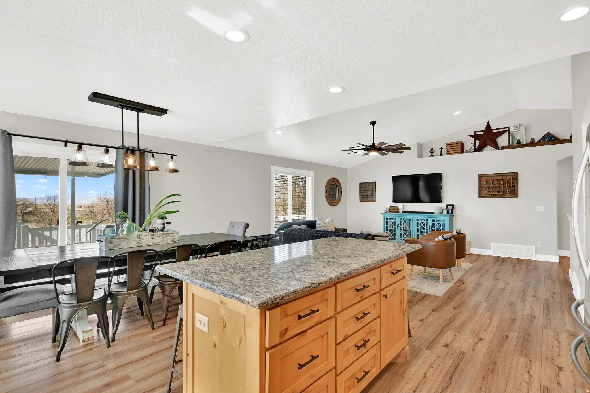 Kitchen with a center island, light wood-style flooring, a kitchen bar, open floor plan, and light stone counters