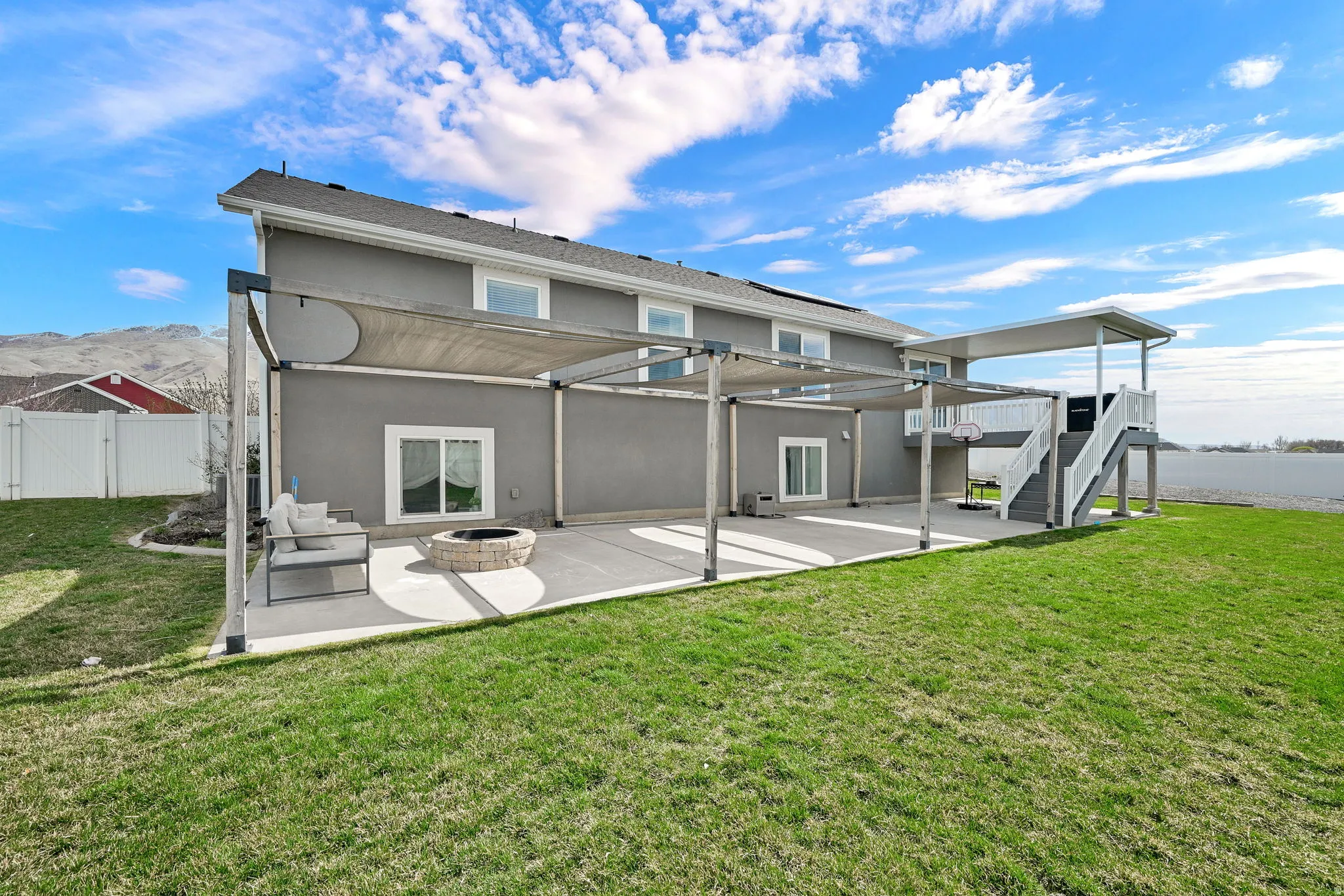 Rear view of house with a patio area, stucco siding, a gate, a fenced backyard, and an outdoor living space with a fire pit