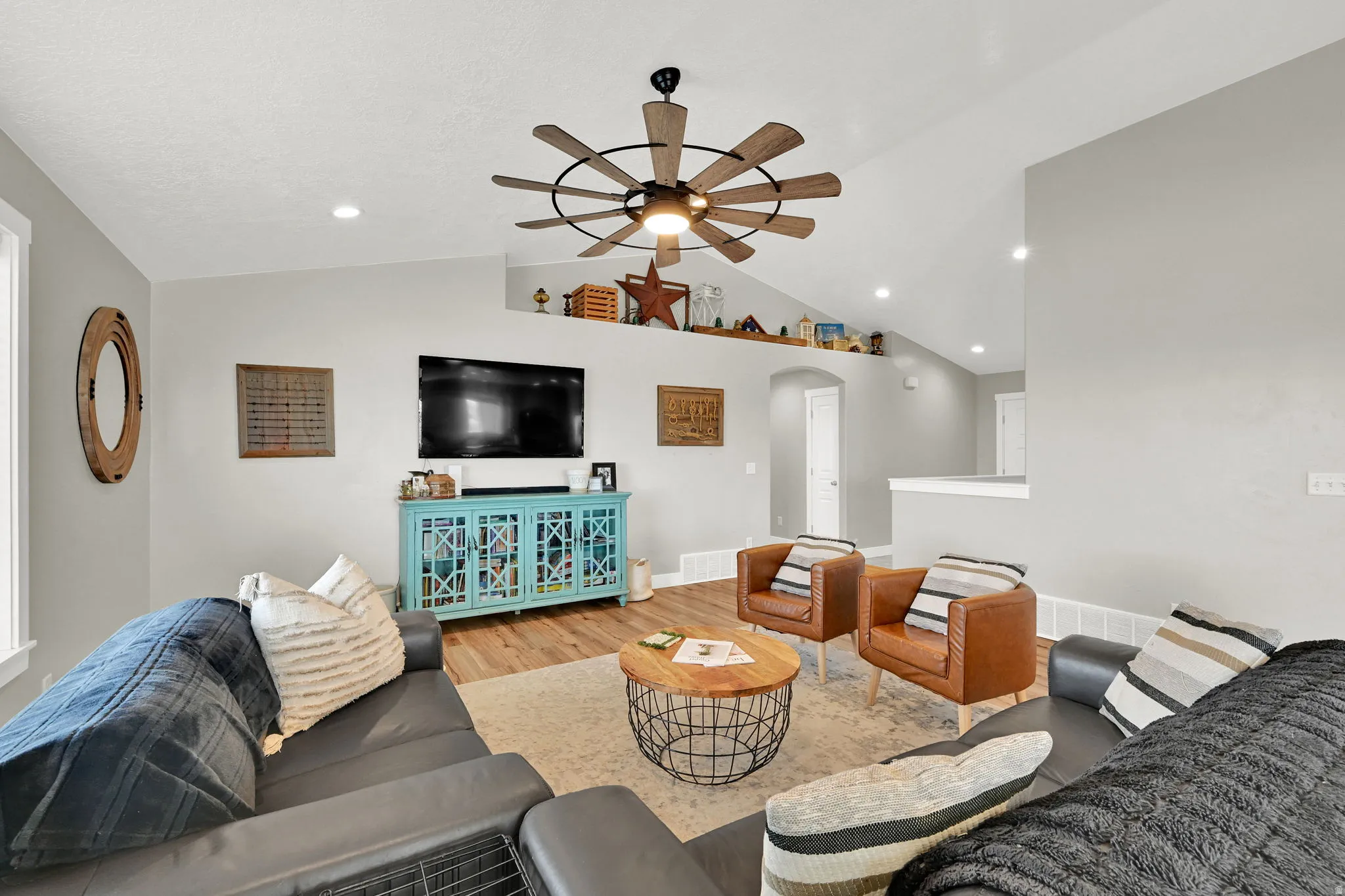Living room with arched walkways, wood finished floors, ceiling fan, lofted ceiling, and recessed lighting