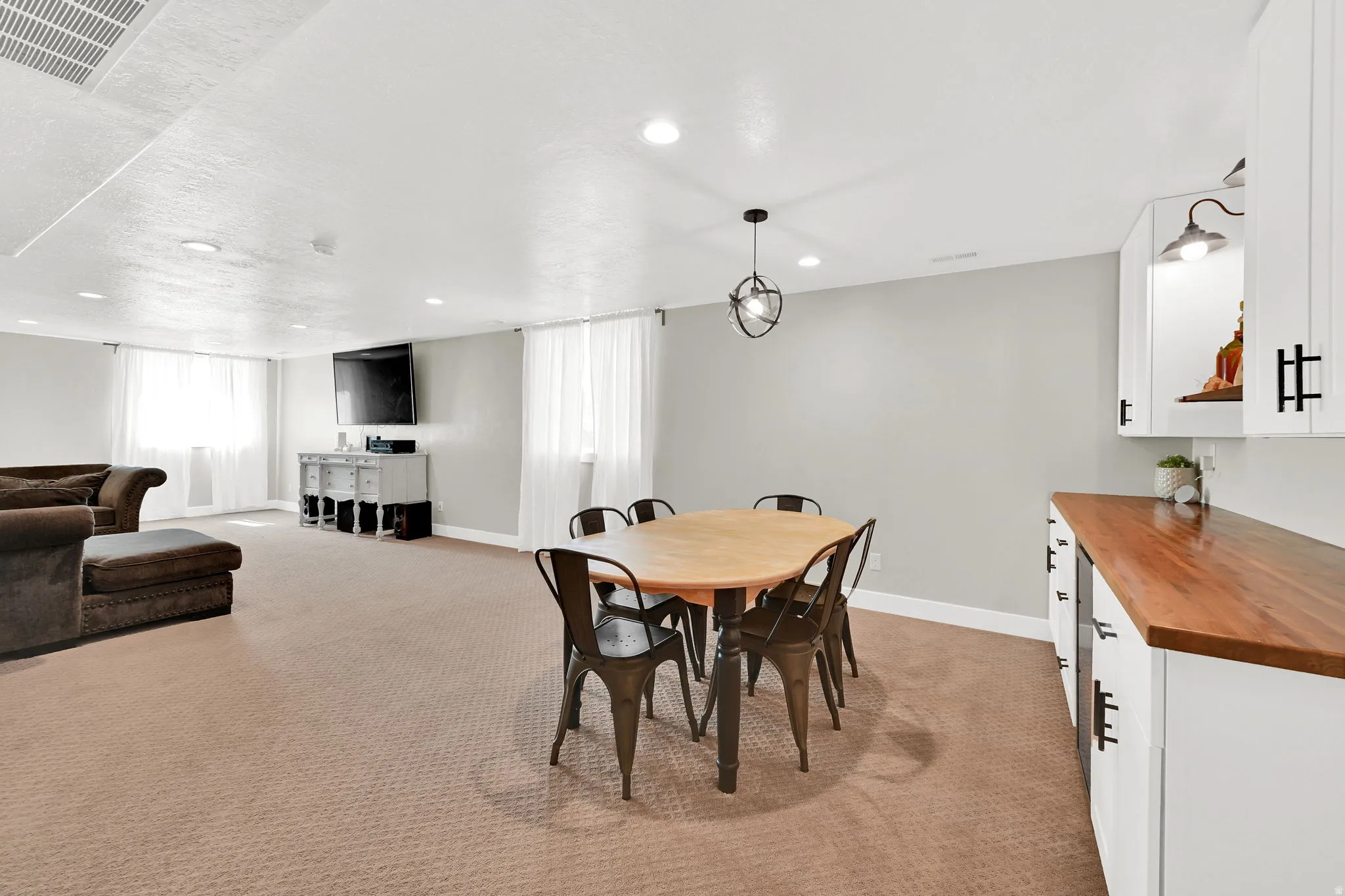 Dining area with light colored carpet and recessed lighting