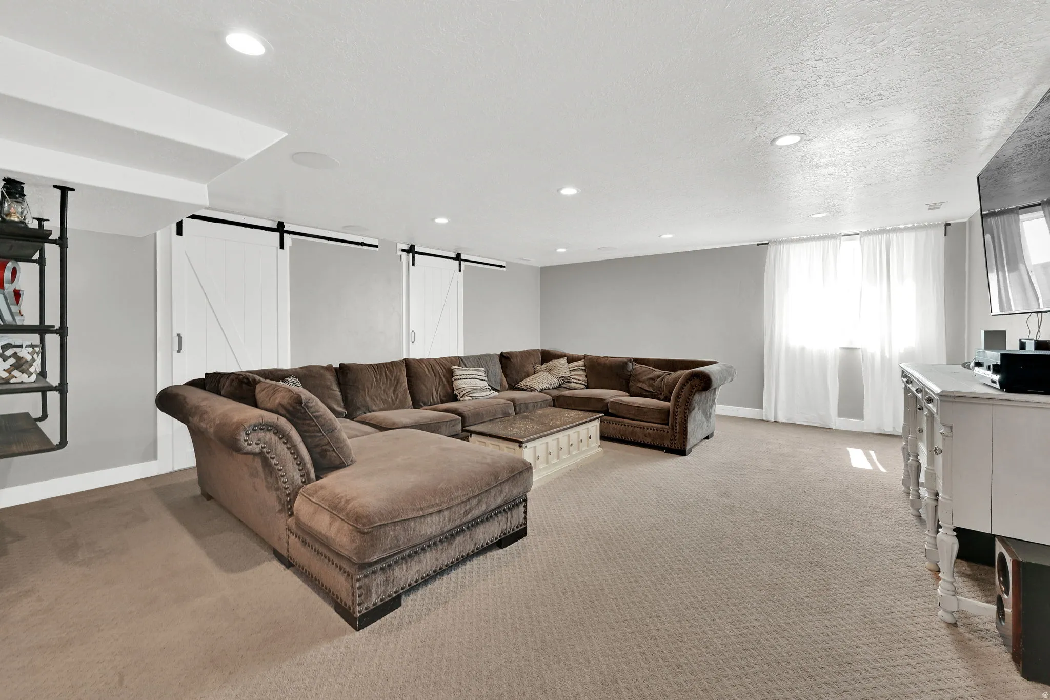 Living area with a barn door, light carpet, and recessed lighting