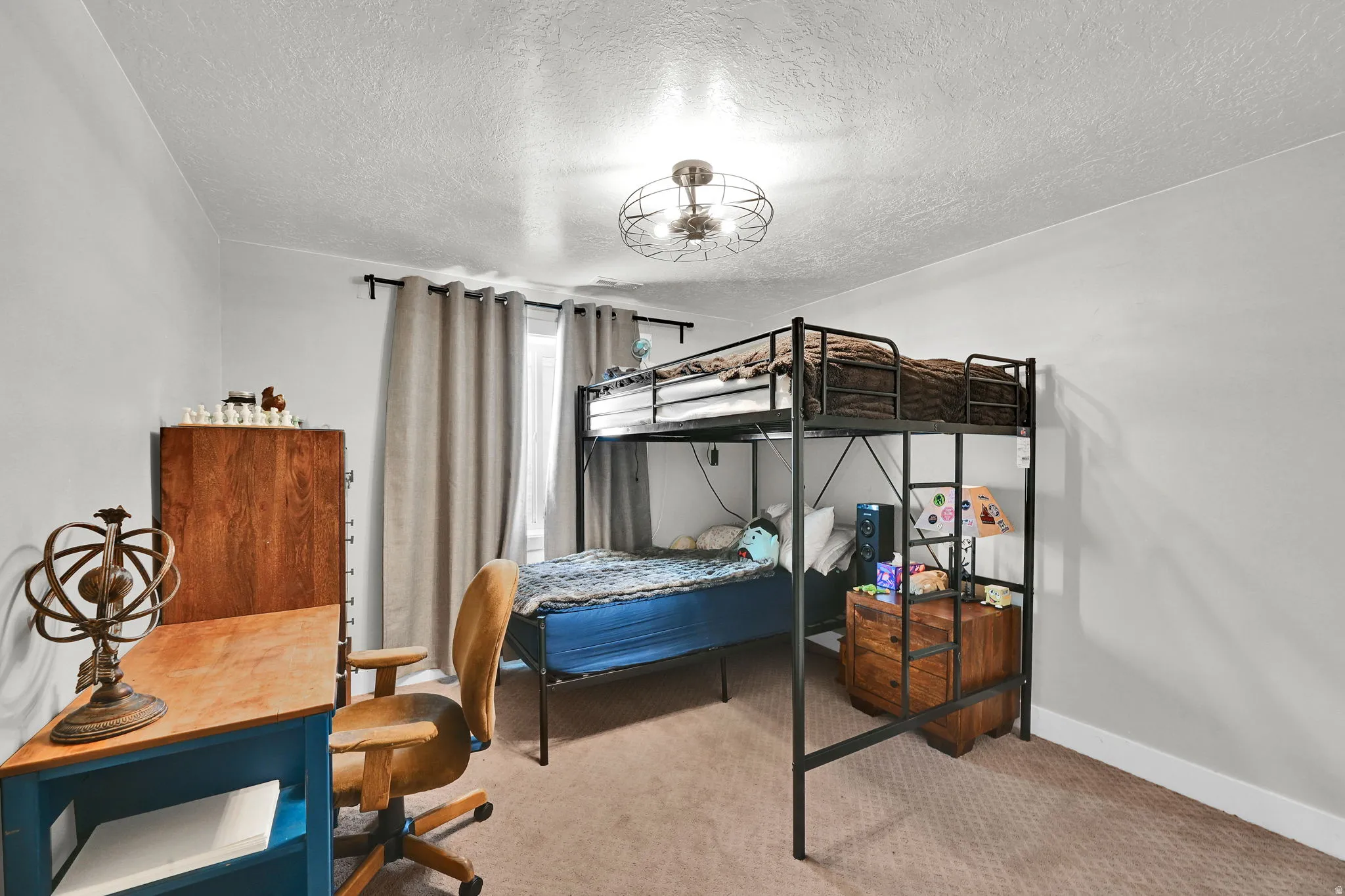 Bedroom featuring a textured ceiling, light colored carpet, and a desk