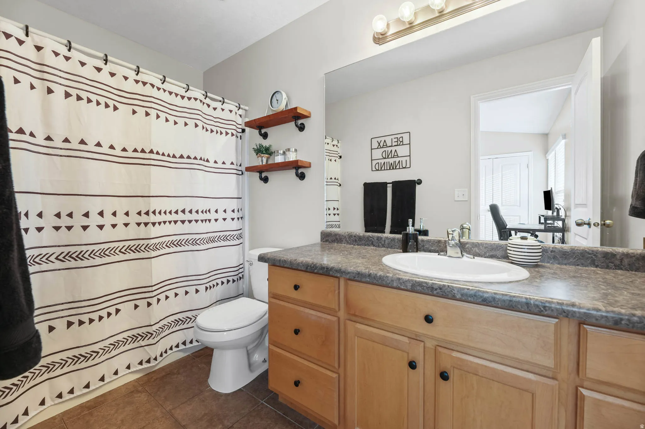 Bathroom with vanity, curtained shower, and dark tile patterned flooring