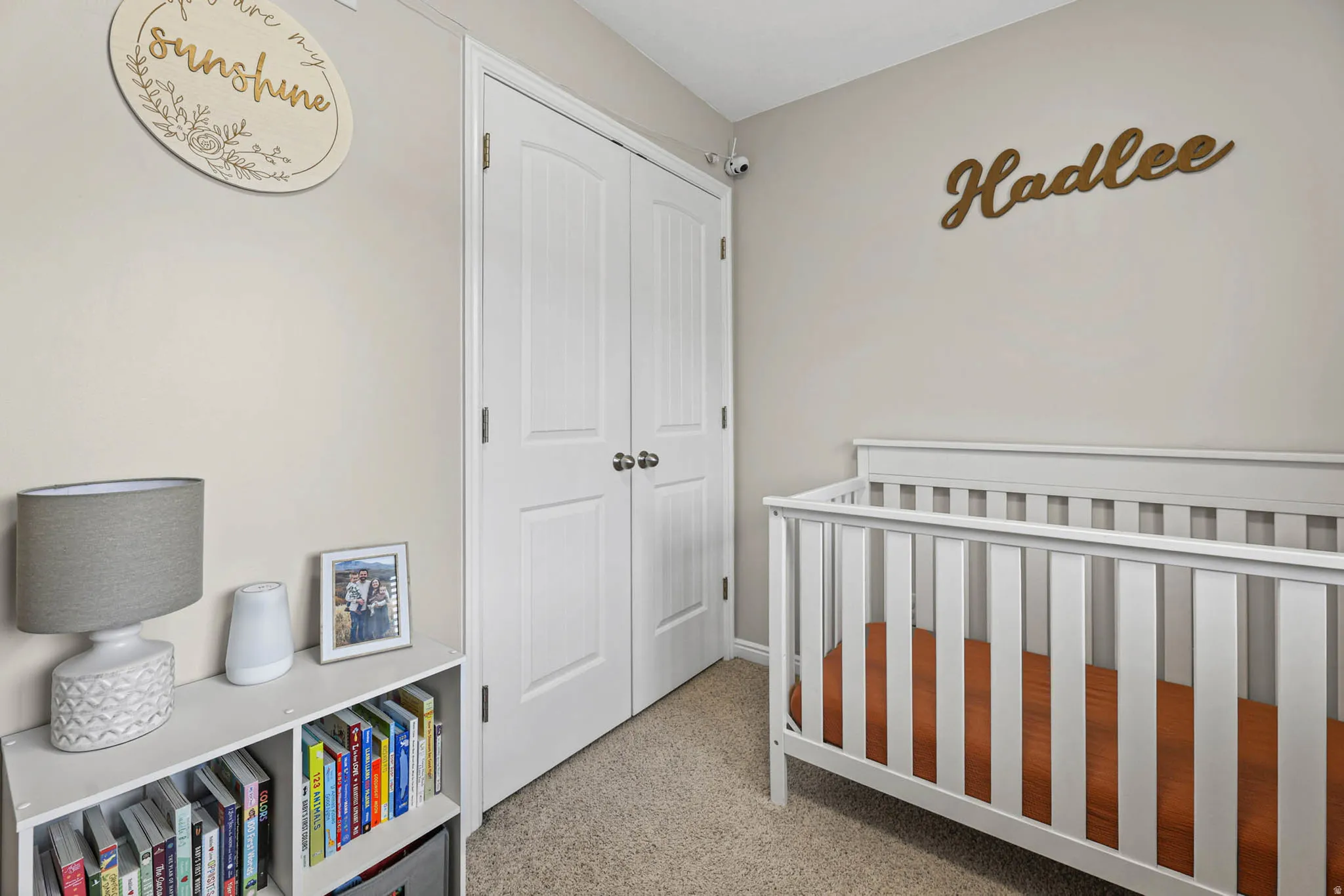 Bedroom featuring a crib, a closet, and light carpet