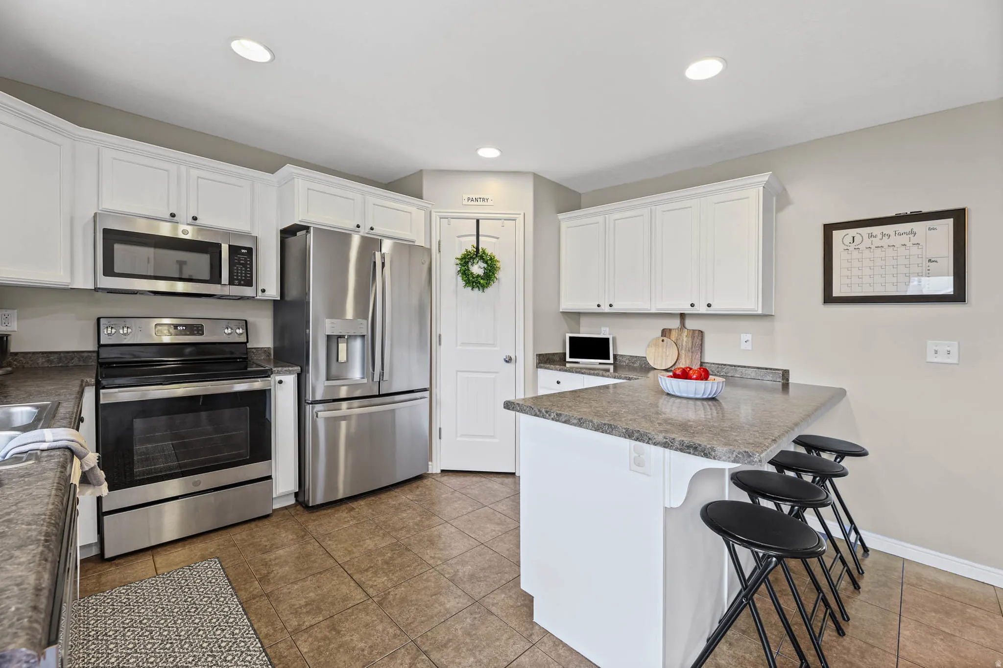 Kitchen with stainless steel appliances, a kitchen breakfast bar, white cabinets, a peninsula, and dark countertops