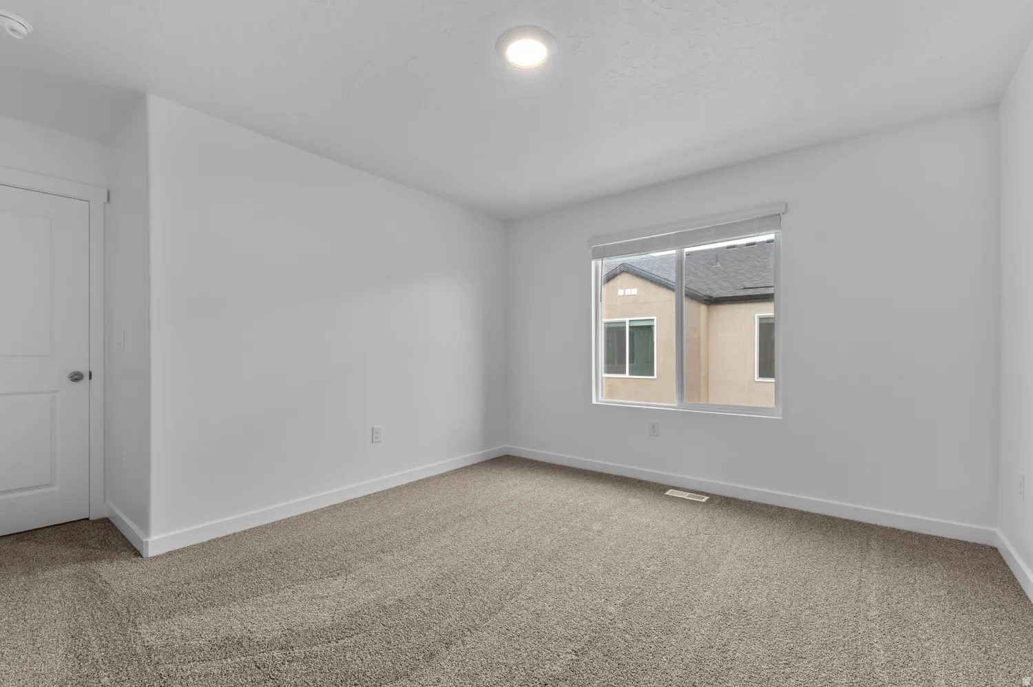 Carpeted spare room with baseboards and a smoke detector