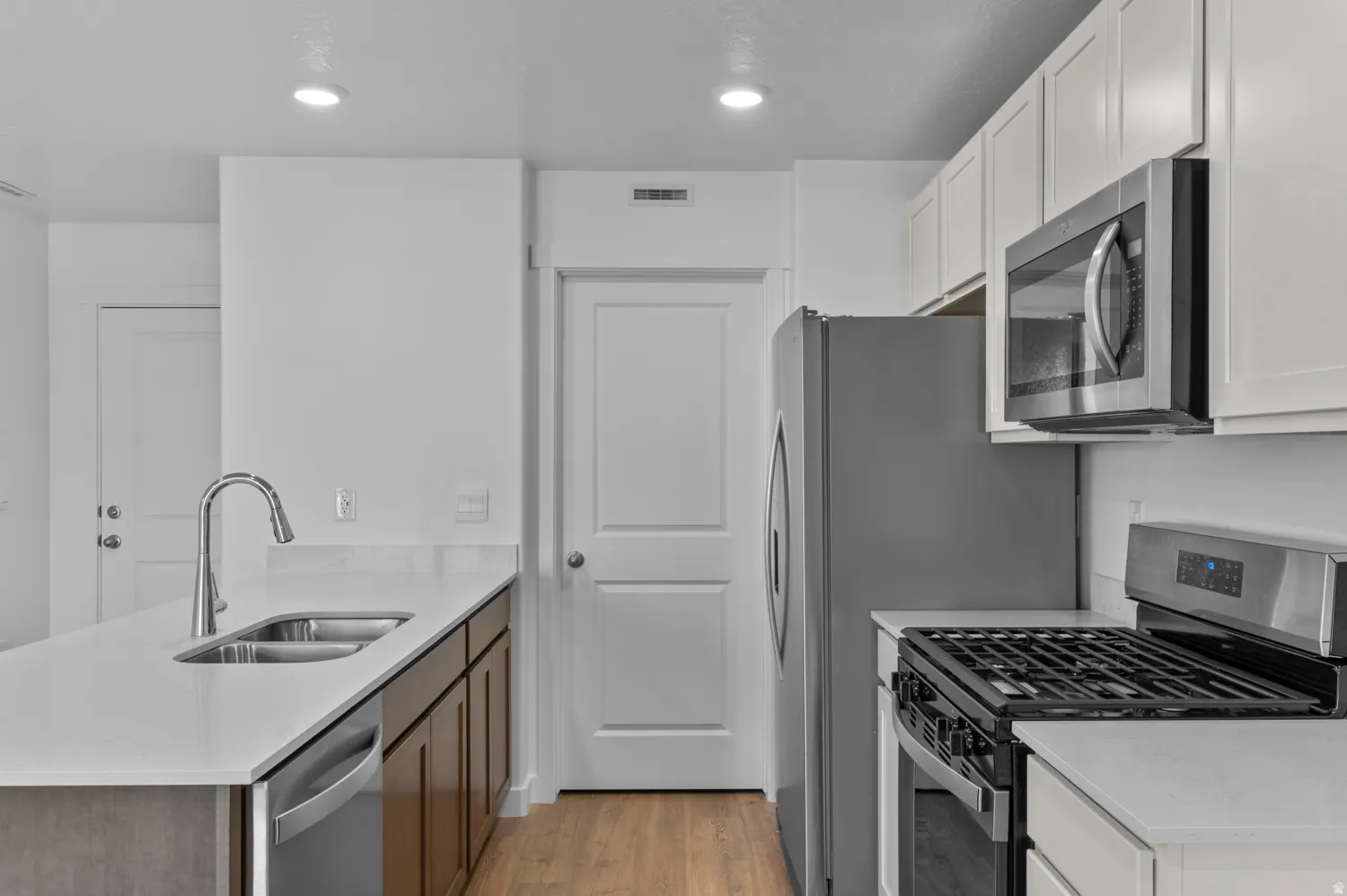 Kitchen featuring stainless steel appliances, light stone counters, a peninsula, light wood-style flooring, and recessed lighting