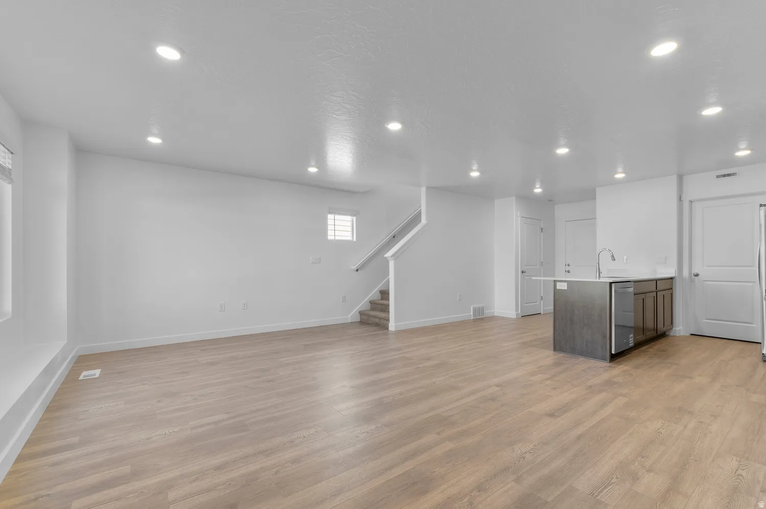 Unfurnished living room with light wood finished floors, recessed lighting, and a textured ceiling