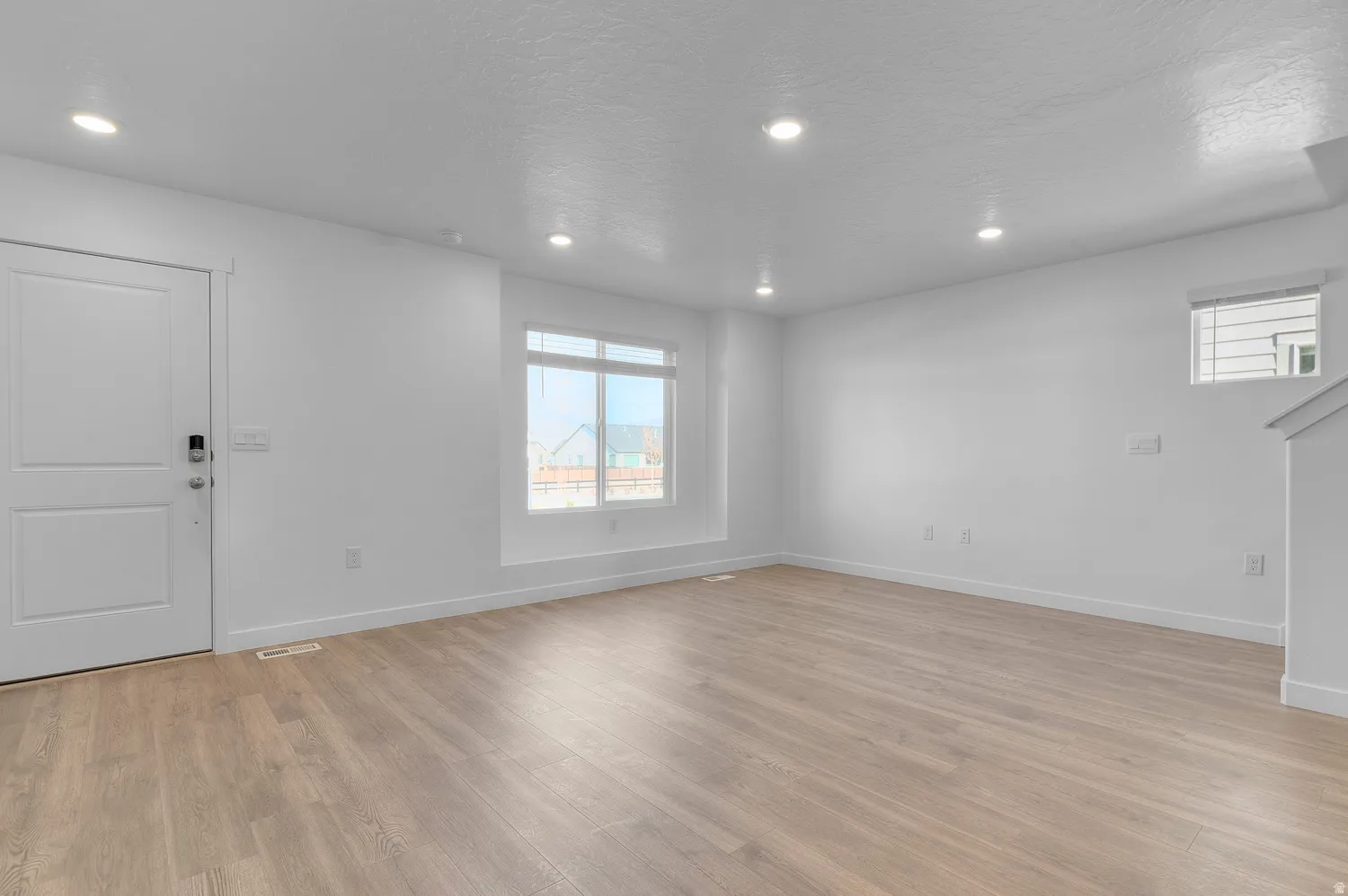 Unfurnished living room featuring light wood-style flooring, recessed lighting, and a textured ceiling
