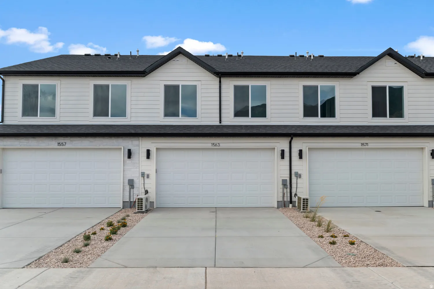 Traditional home with a shingled roof, an attached garage, and driveway