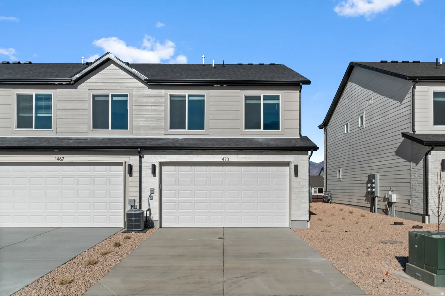 View of front facade featuring concrete driveway, an attached garage, and a shingled roof