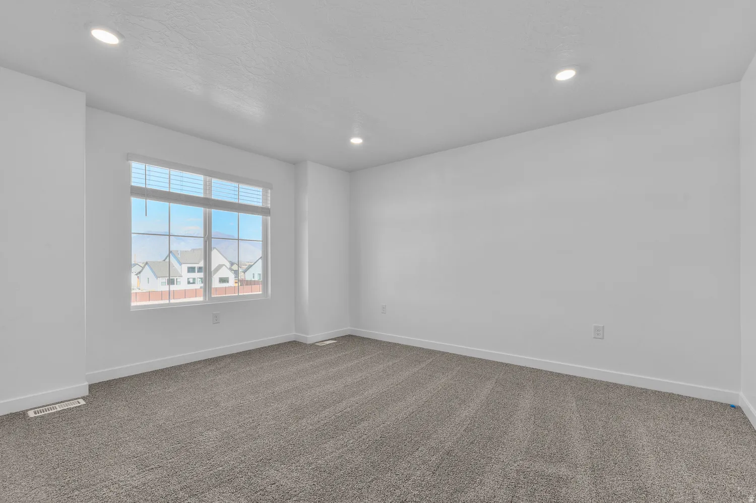 Carpeted spare room with baseboards and recessed lighting