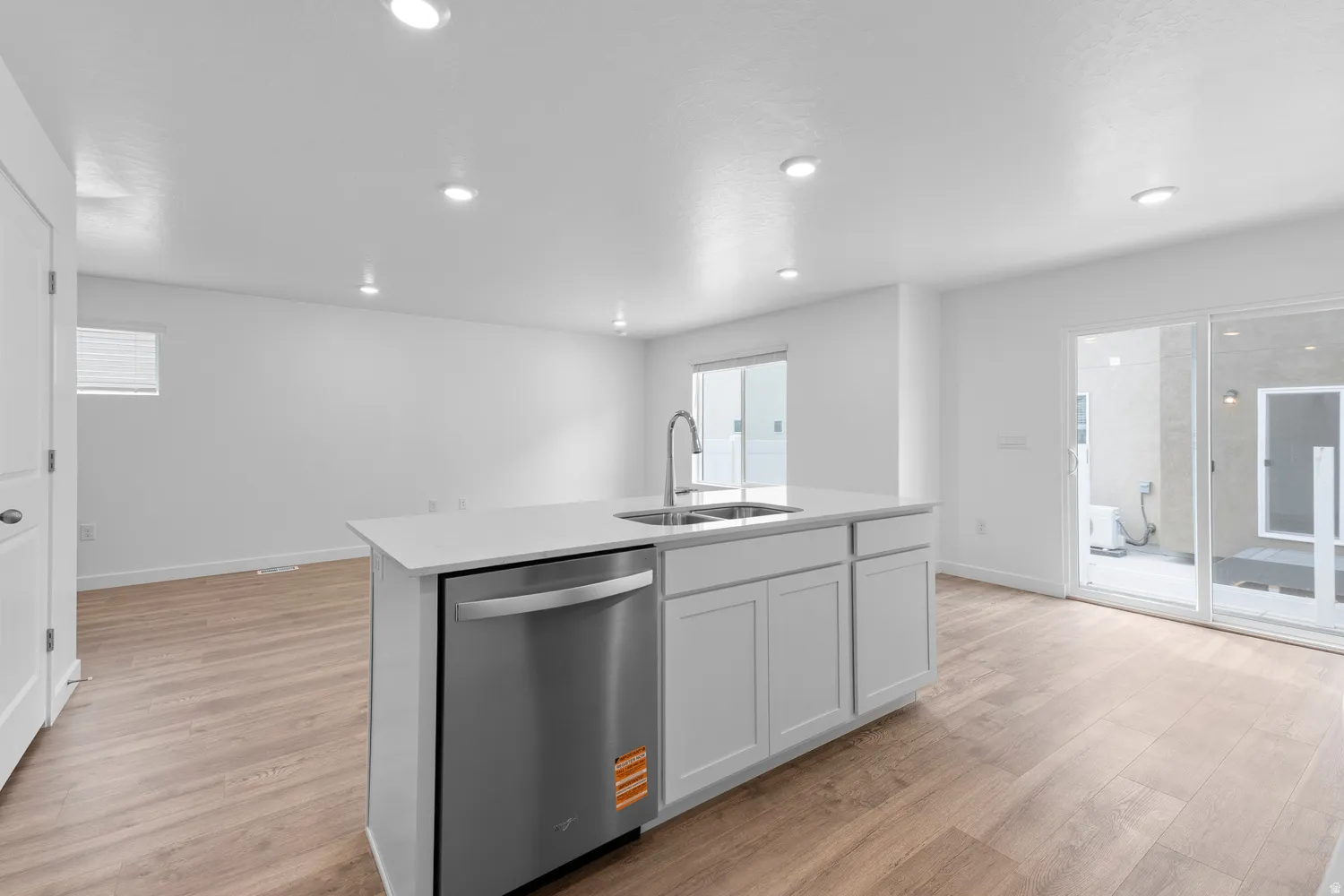 Kitchen featuring dishwasher, light wood-style floors, a kitchen island with sink, white cabinetry, and recessed lighting