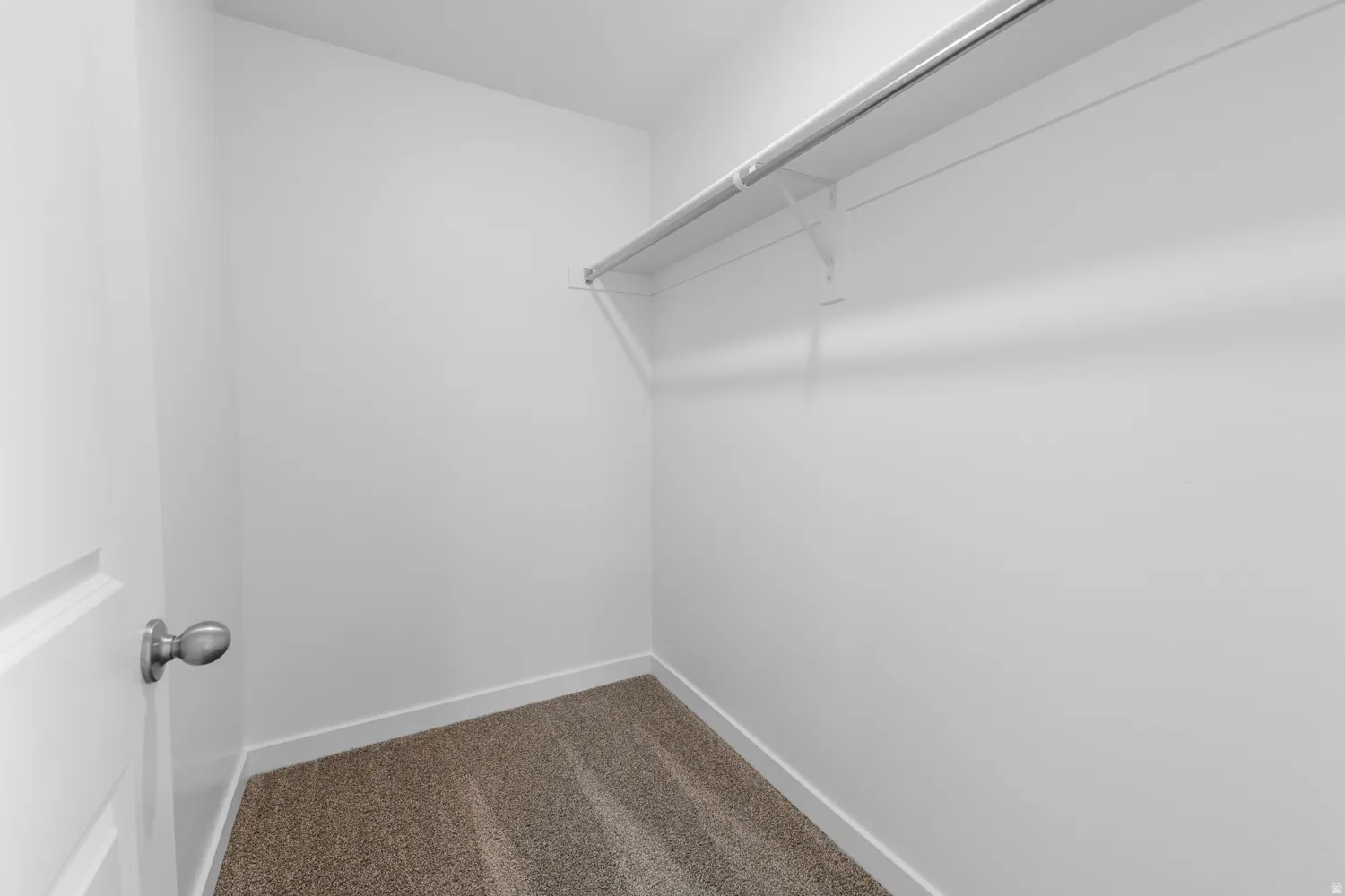 Walk in closet with dark colored carpet