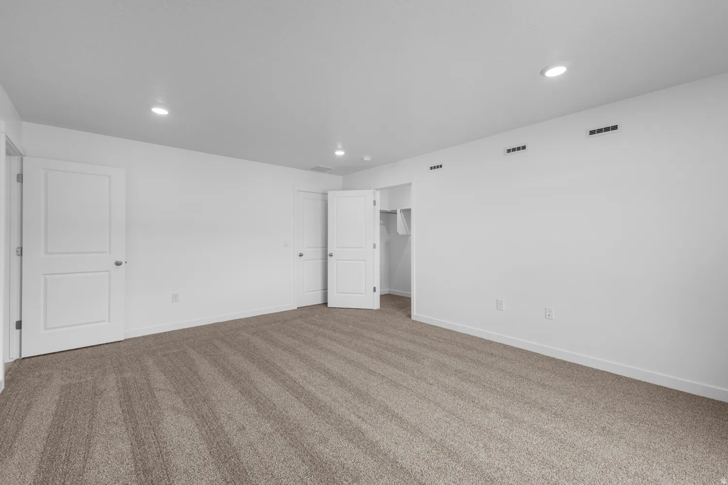 Unfurnished bedroom with a spacious closet, carpet, and recessed lighting
