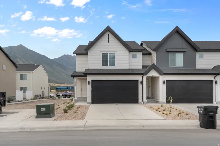 View of front facade with a mountain view, a garage, driveway, and a shingled roof