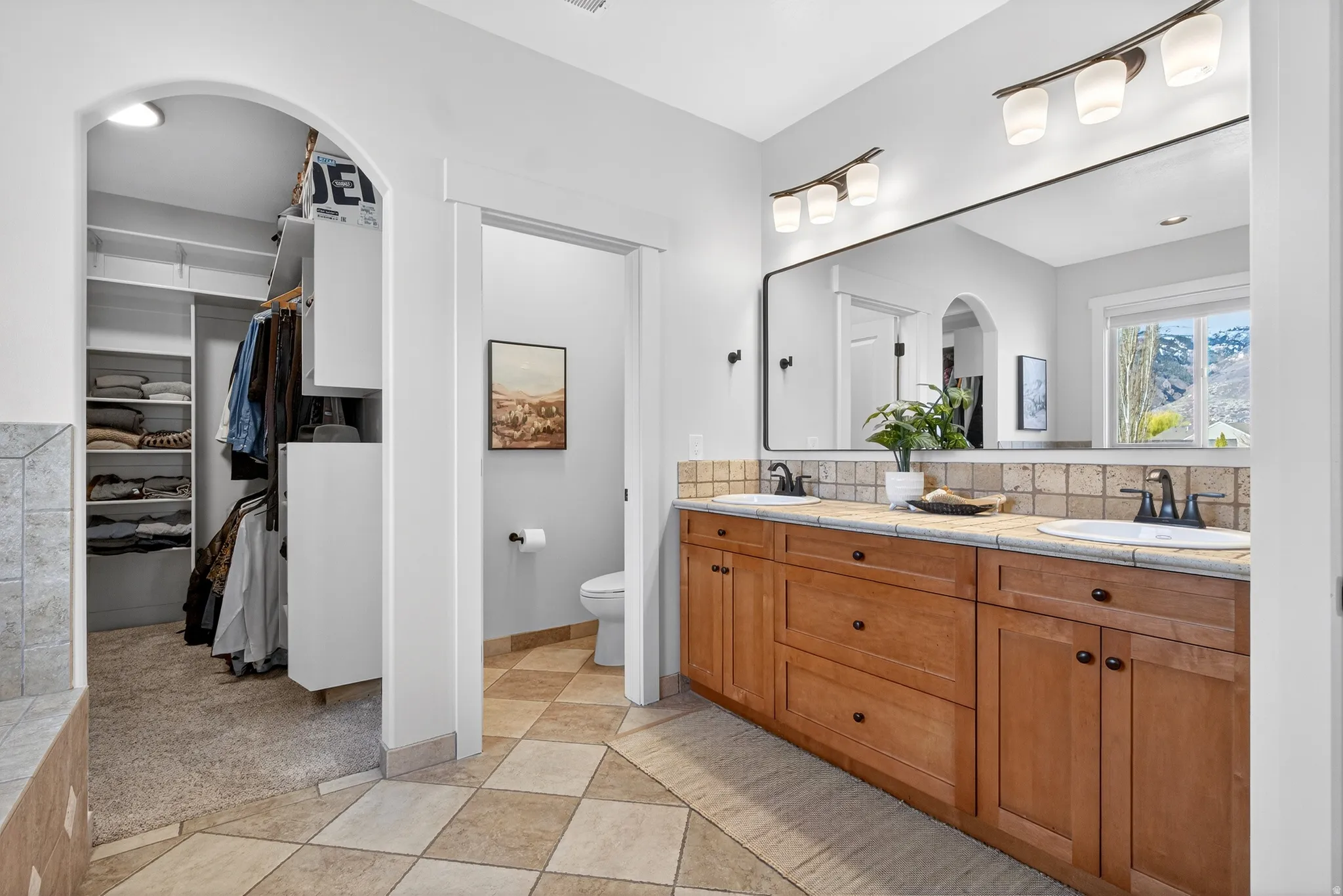 Bathroom with double vanity, a walk in closet, and light tile patterned flooring