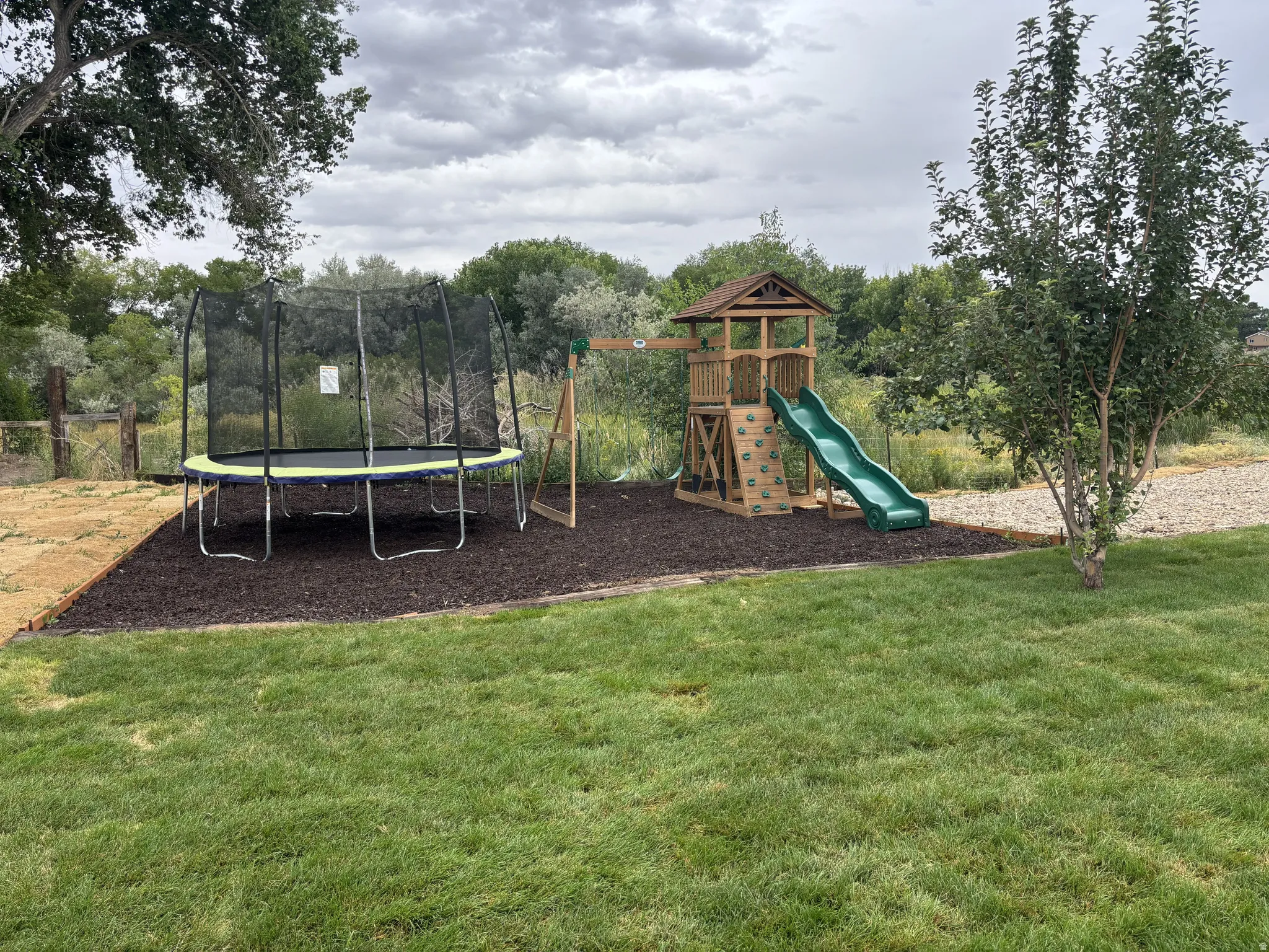 View of playground featuring a trampoline and a yard