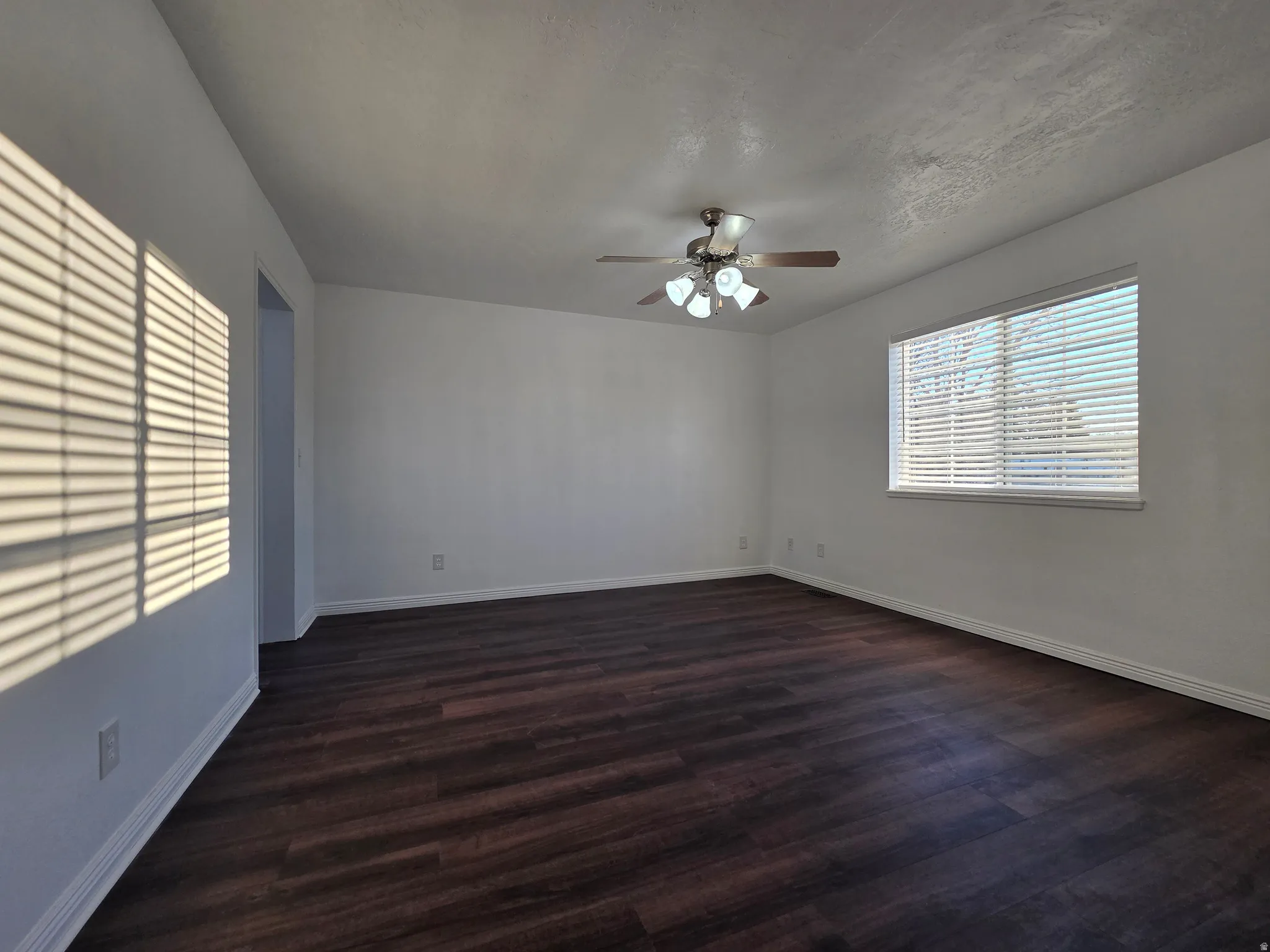 Empty room featuring a ceiling fan and dark wood finished floors