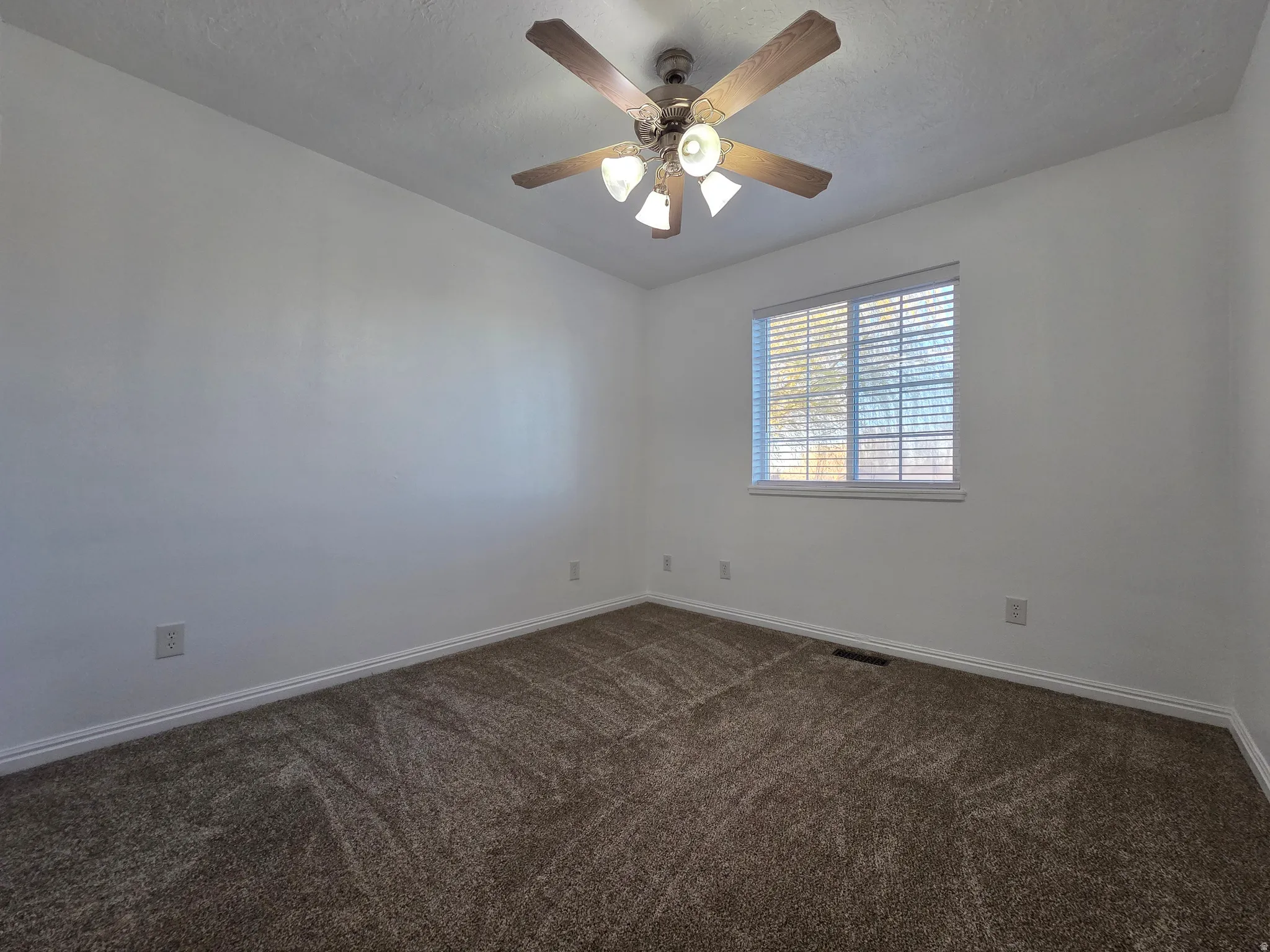 Empty room with dark carpet and ceiling fan