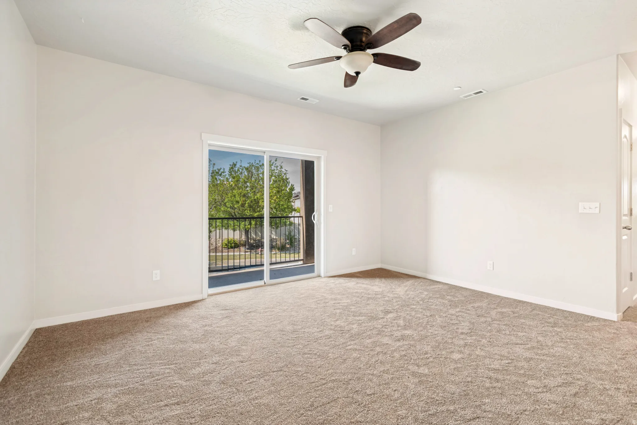 Expansive room featuring light-colored walls and neutral carpeting