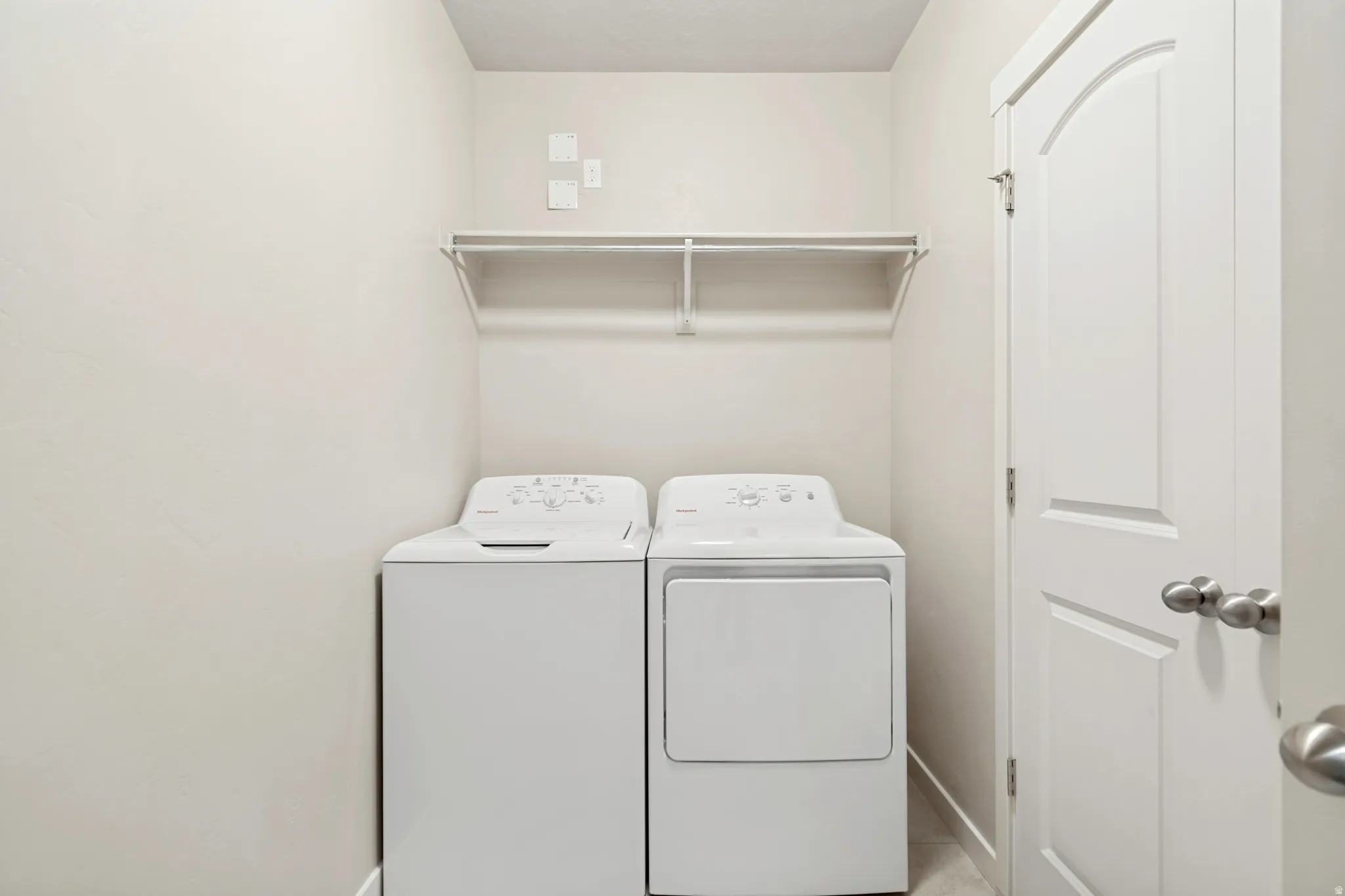 Dedicated laundry area featuring a shelf and rod for organization, a white top-load washing machine, and a white front-load dryer
