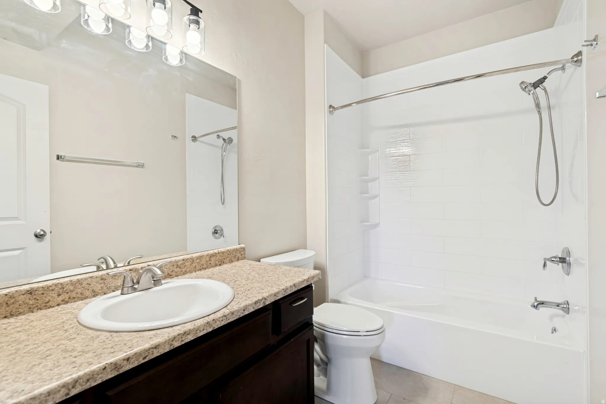 Bathroom featuring a vanity with an oval undermount sink, a speckled countertop, and a dark wood-finish cabinet