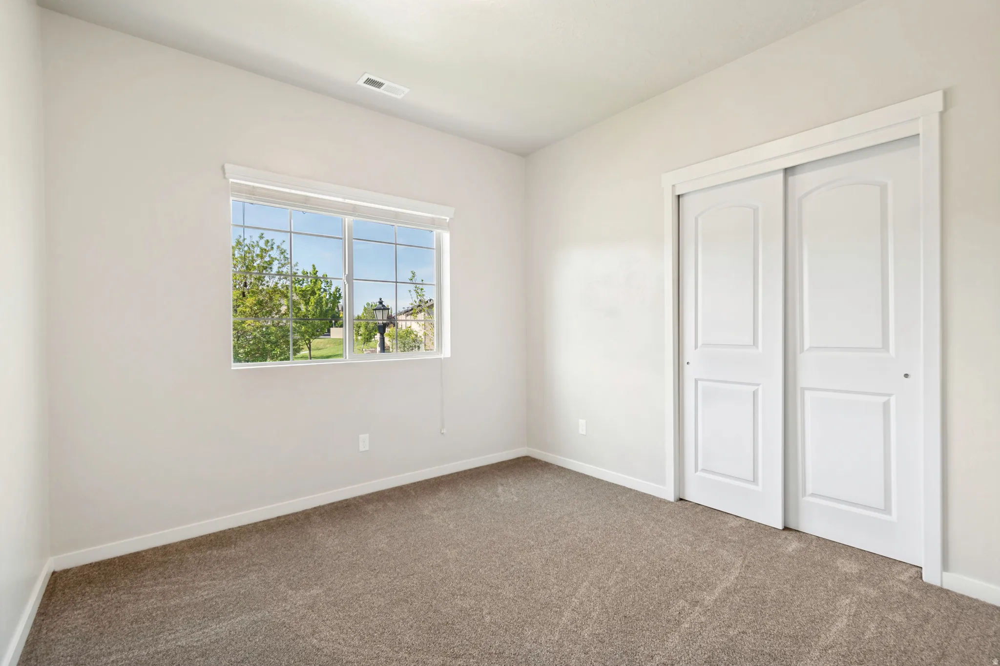 Carpeted room featuring a large window with white blinds, offering abundant natural light