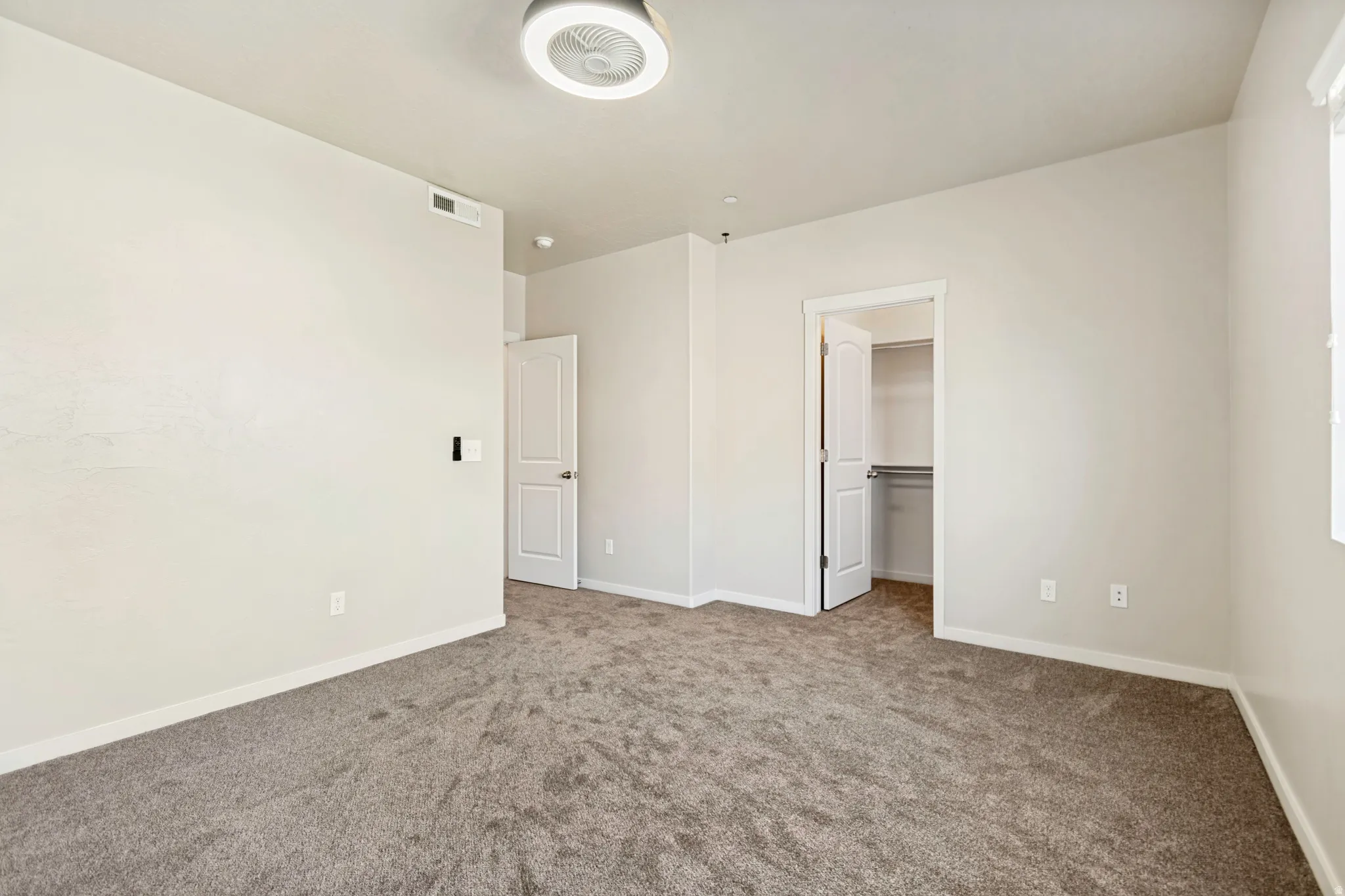 Neutral tone walls with textured carpeting, a flush mount ceiling light fixture, and white trim