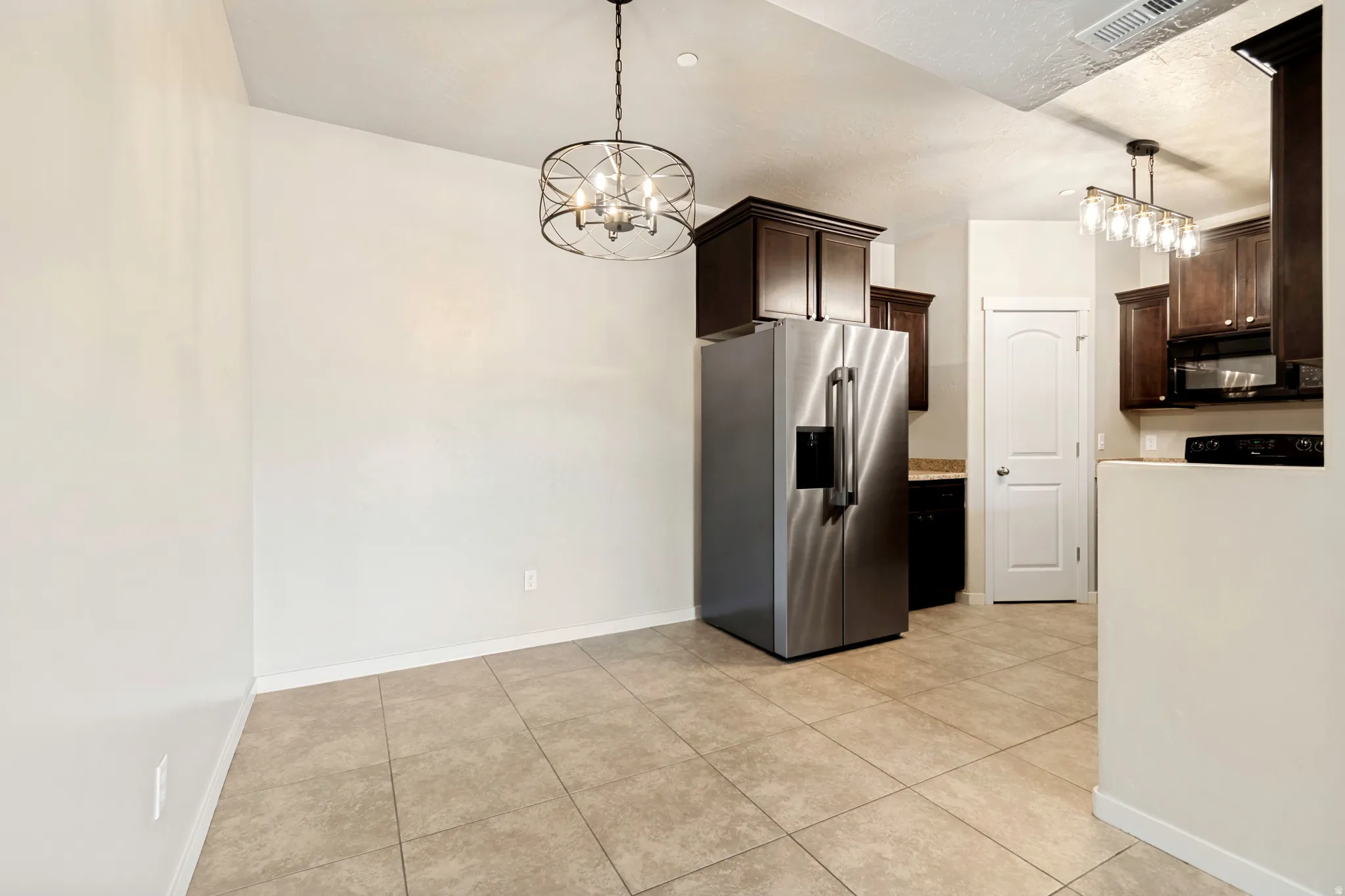 Tiled flooring throughout the space, featuring a dining area with a circular chandelier