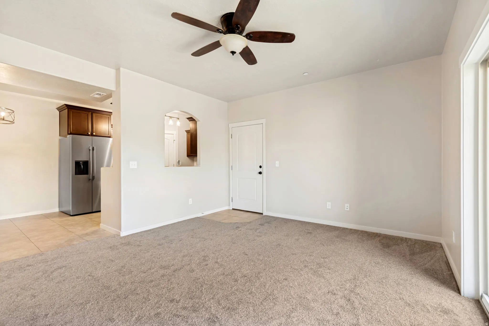 Open-concept living area featuring a ceiling fan, neutral carpet flooring, and light-toned walls