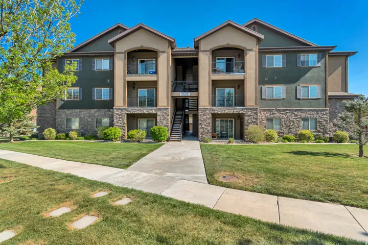 Multi-story property featuring a stone and stucco exterior, multiple private balconies, and ground-level patios