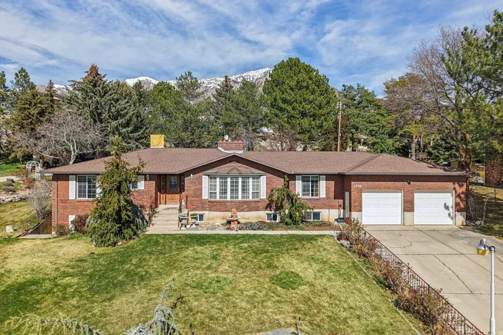 Single story home with brick siding, a garage, concrete driveway, a front lawn, and a chimney