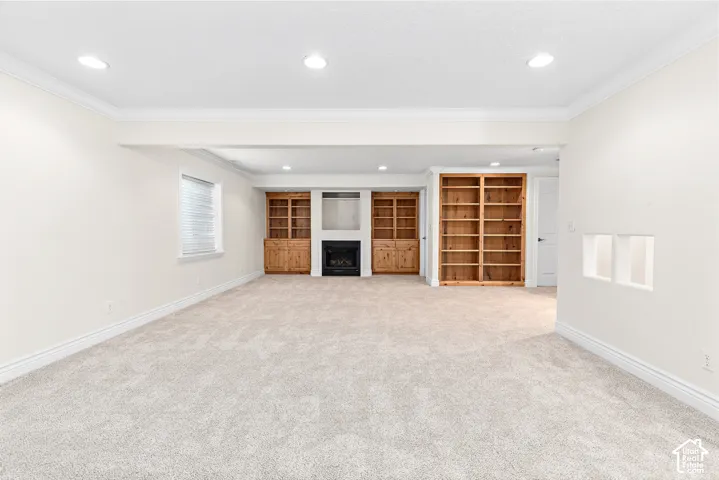 Recessed lighting, wood-finish built-in shelving, a fireplace, and neutral carpeting
