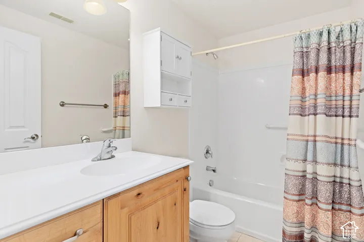 Bathroom featuring a light wood-finish vanity with a white countertop and integrated sink, a large wall mirror, and a white tub with shower
