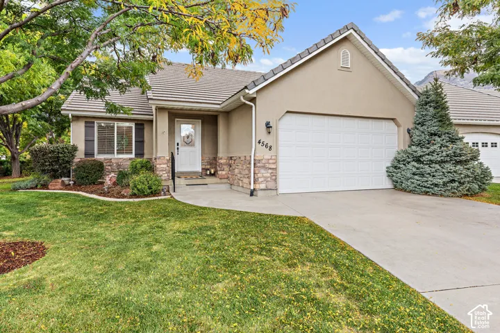 Stucco exterior with stone accents, attached garage, and a concrete driveway