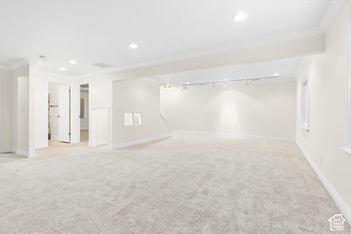 Open-concept room featuring light-toned carpeting, recessed lighting, crown molding, and a window with blinds