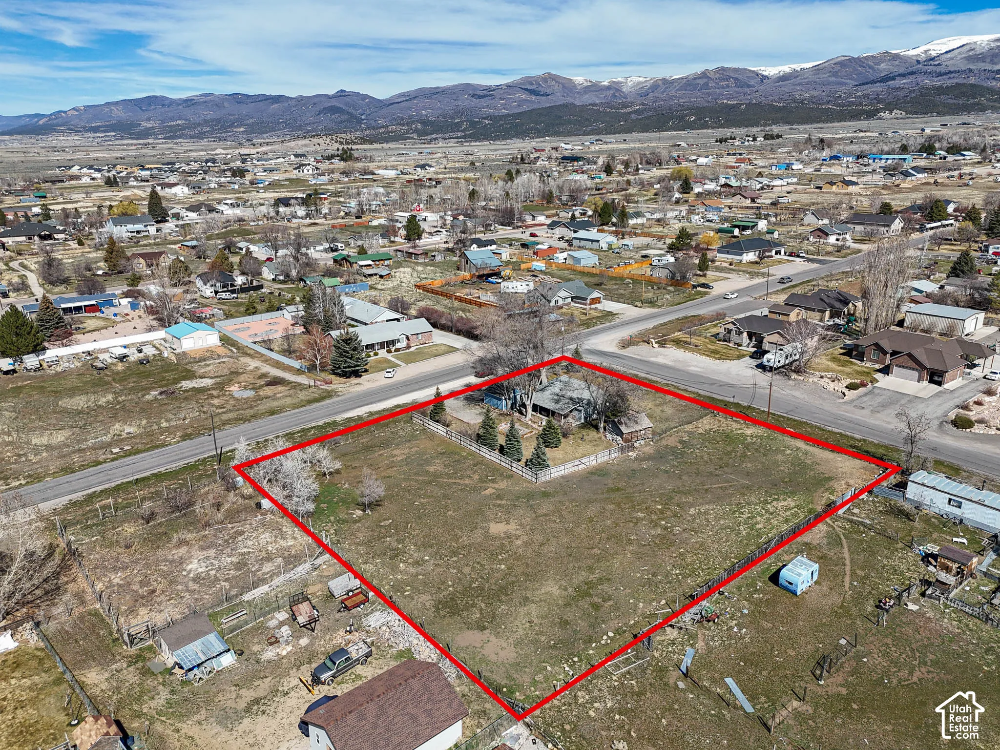 Expansive lot featuring perimeter fencing, mature evergreen trees, and direct mountain backdrops