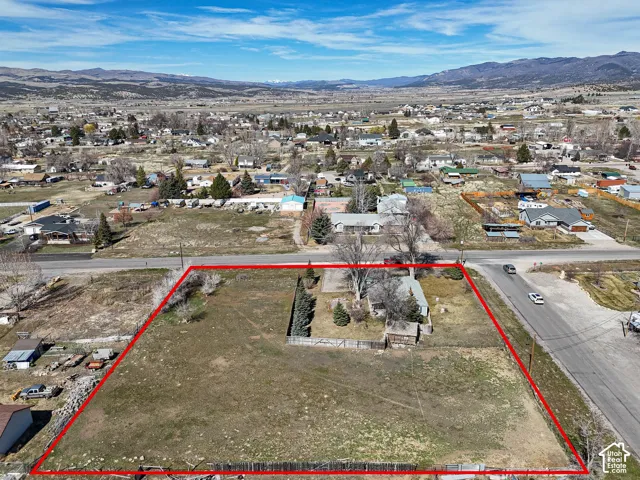 Expansive corner lot featuring mature trees, a fenced perimeter, and mountainous scenery