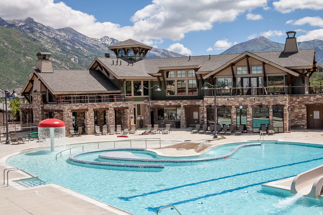 Community pool featuring a water slide, a mountain view, a patio area, a water play area, and a balcony