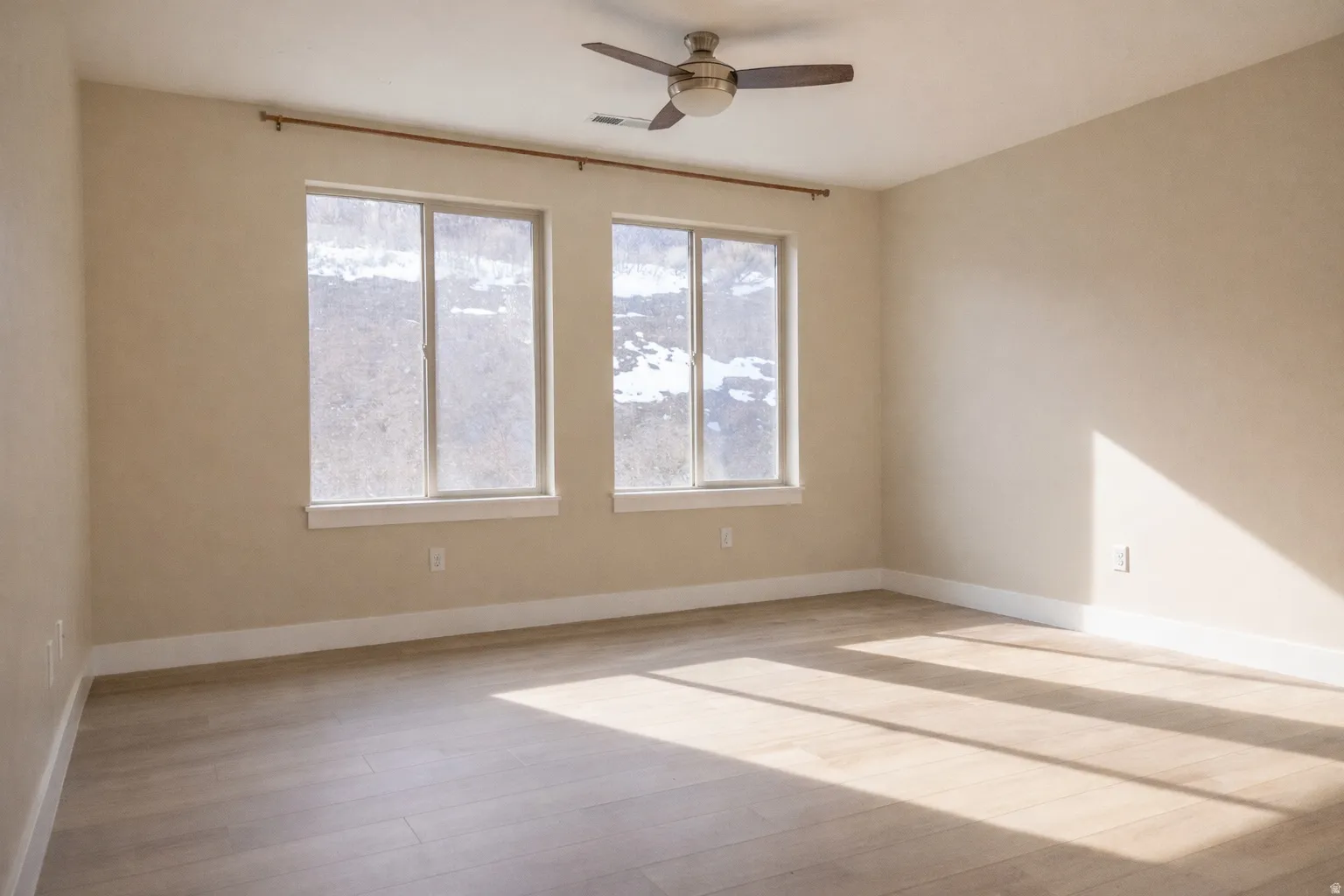 Unfurnished room featuring light wood-type flooring, a ceiling fan, and plenty of natural light