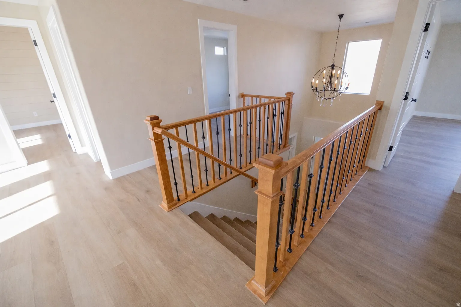 Staircase with suspended lighting and wood finished floors