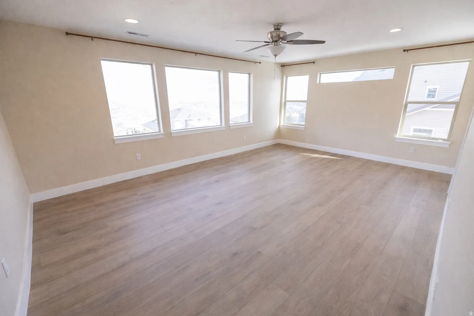 Spare room featuring light wood-style flooring, ceiling fan, and recessed lighting